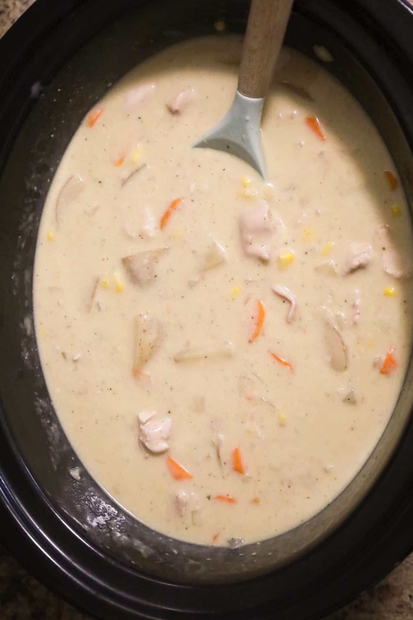 chicken stew being stirred in a crock pot