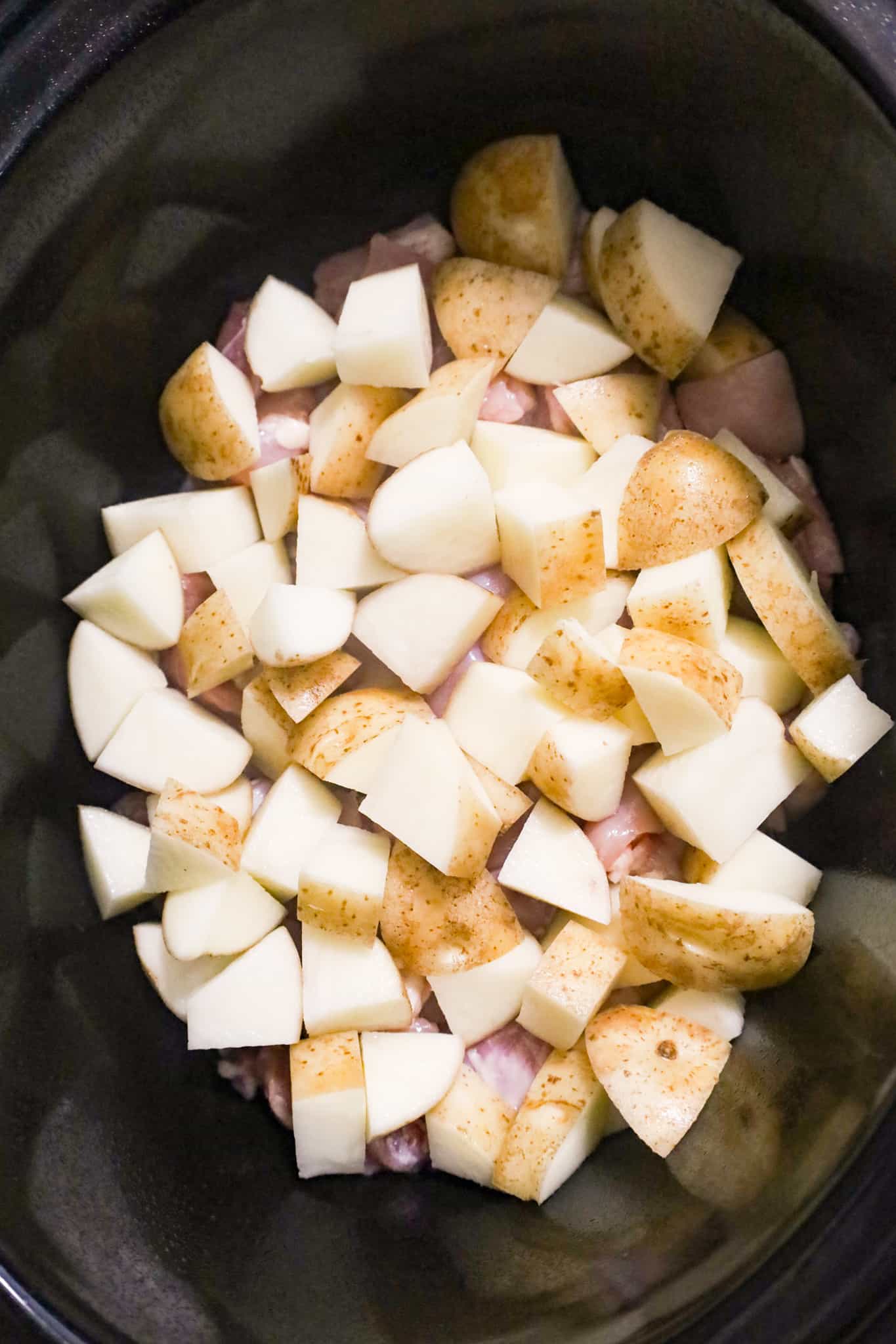 russet potato chunks on top of chicken chunks in a crock pot
