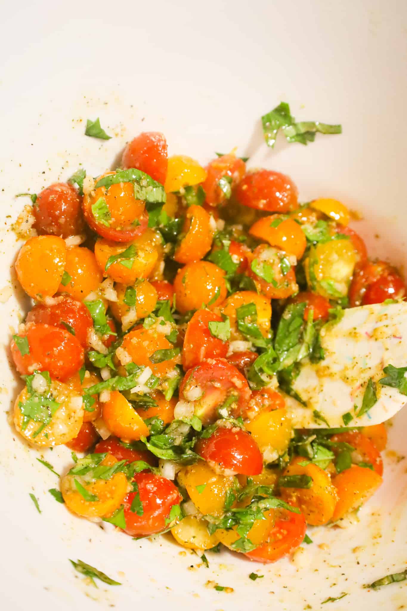 cherry tomato, basil, parley and olive oil mixture in a mixing bowl