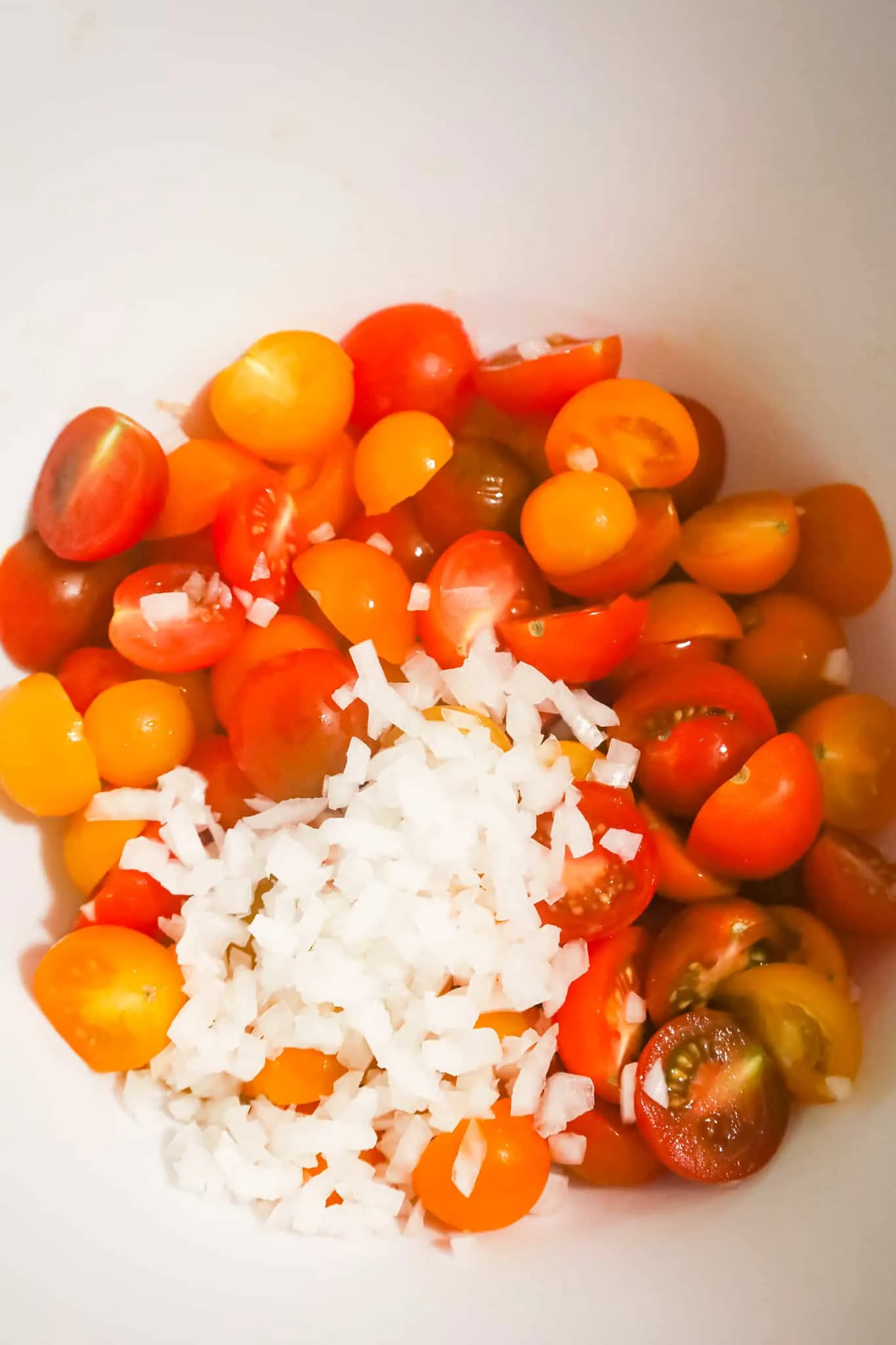 diced onions and halved cherry tomatoes in a mixing bowl