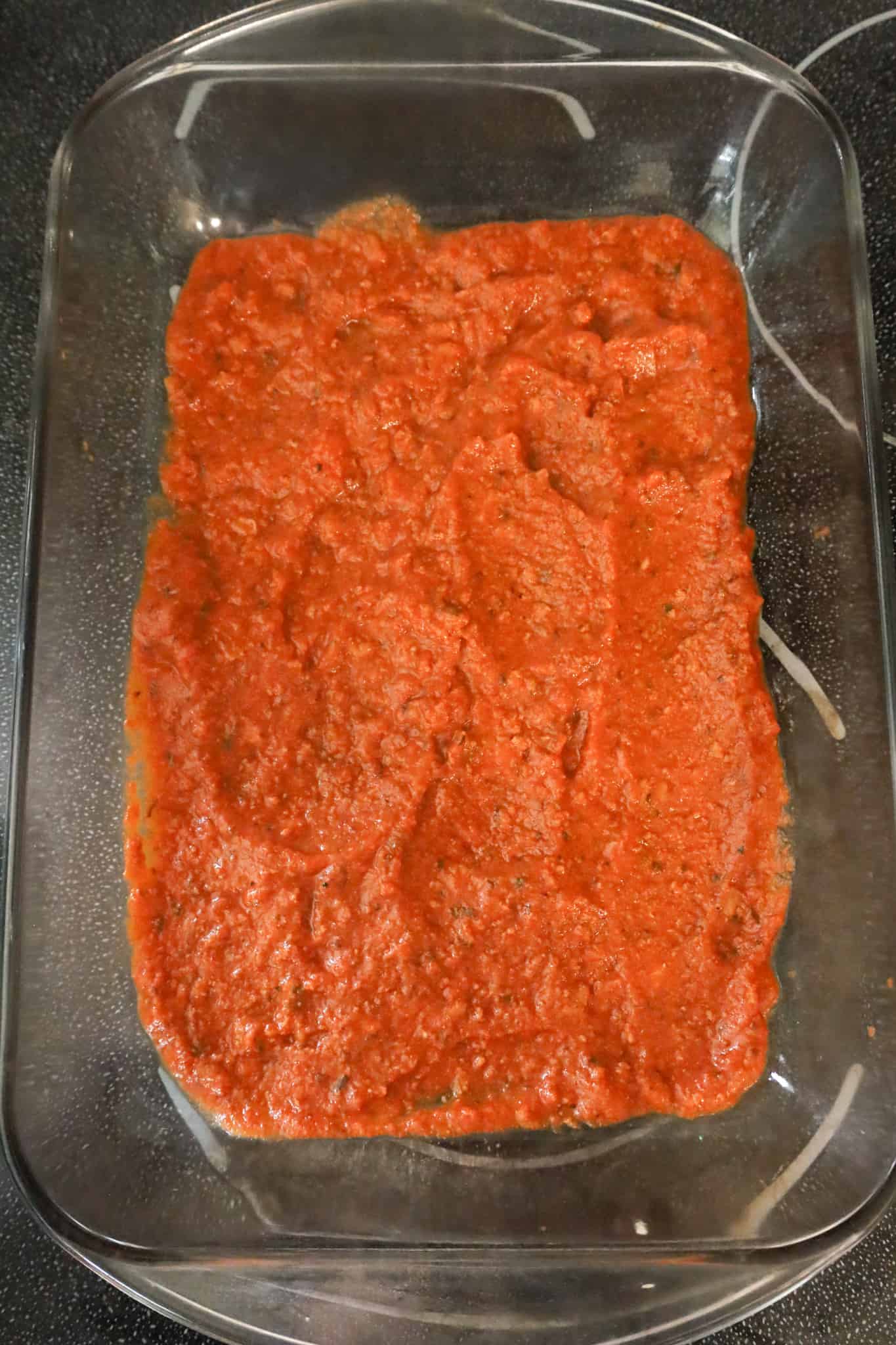 bolognese sauce in the bottom of a 9 x 13 inch baking dish