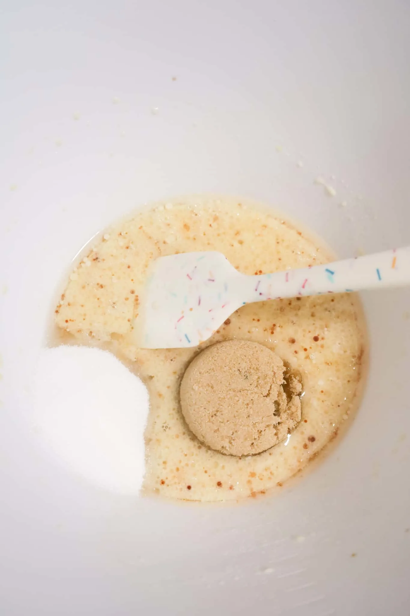 granulated sugar and brown sugar added to a bowl with milk, egg and vanilla mixture.