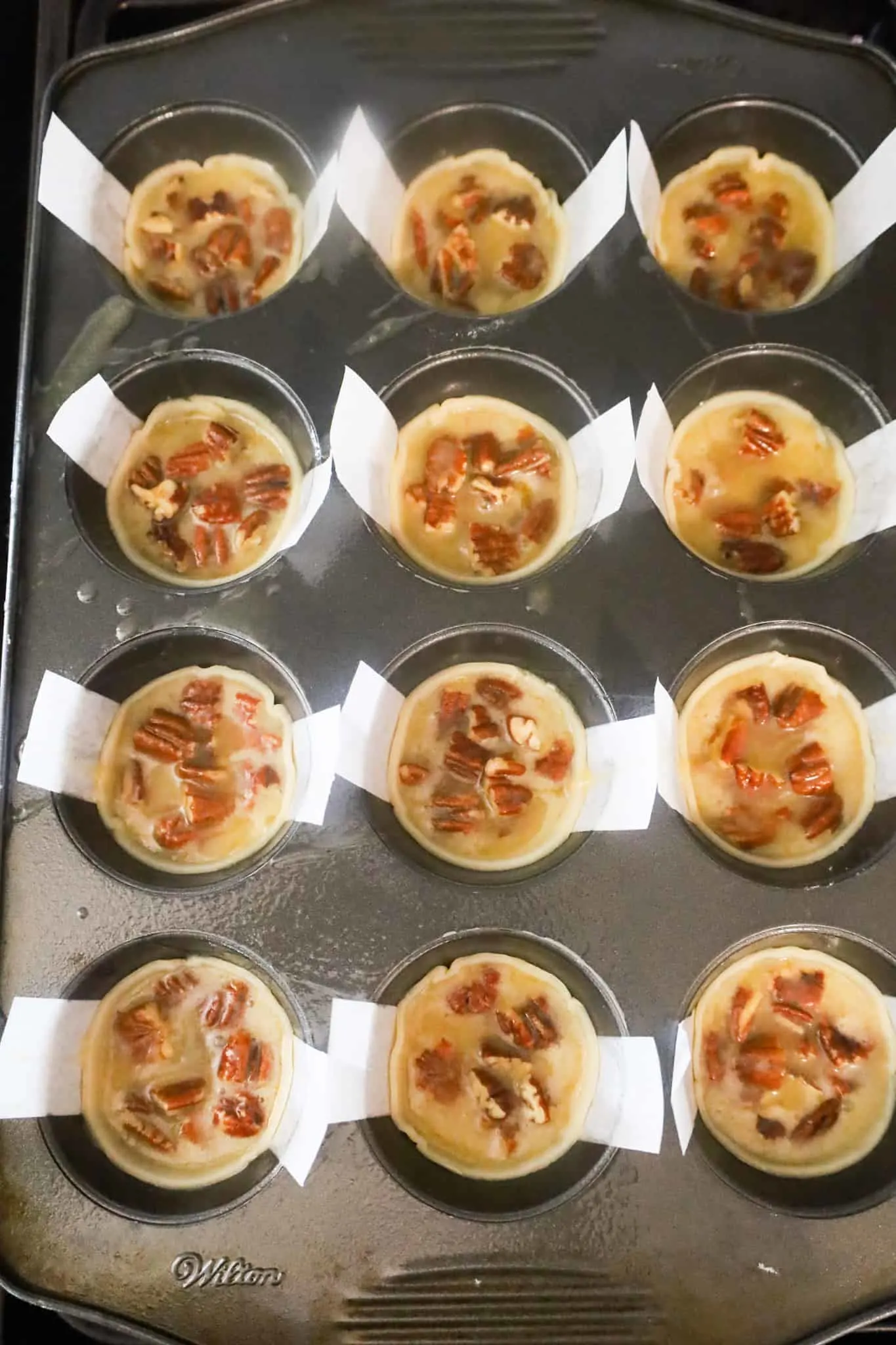 pecan pie filling in pastry shells in a muffin tin