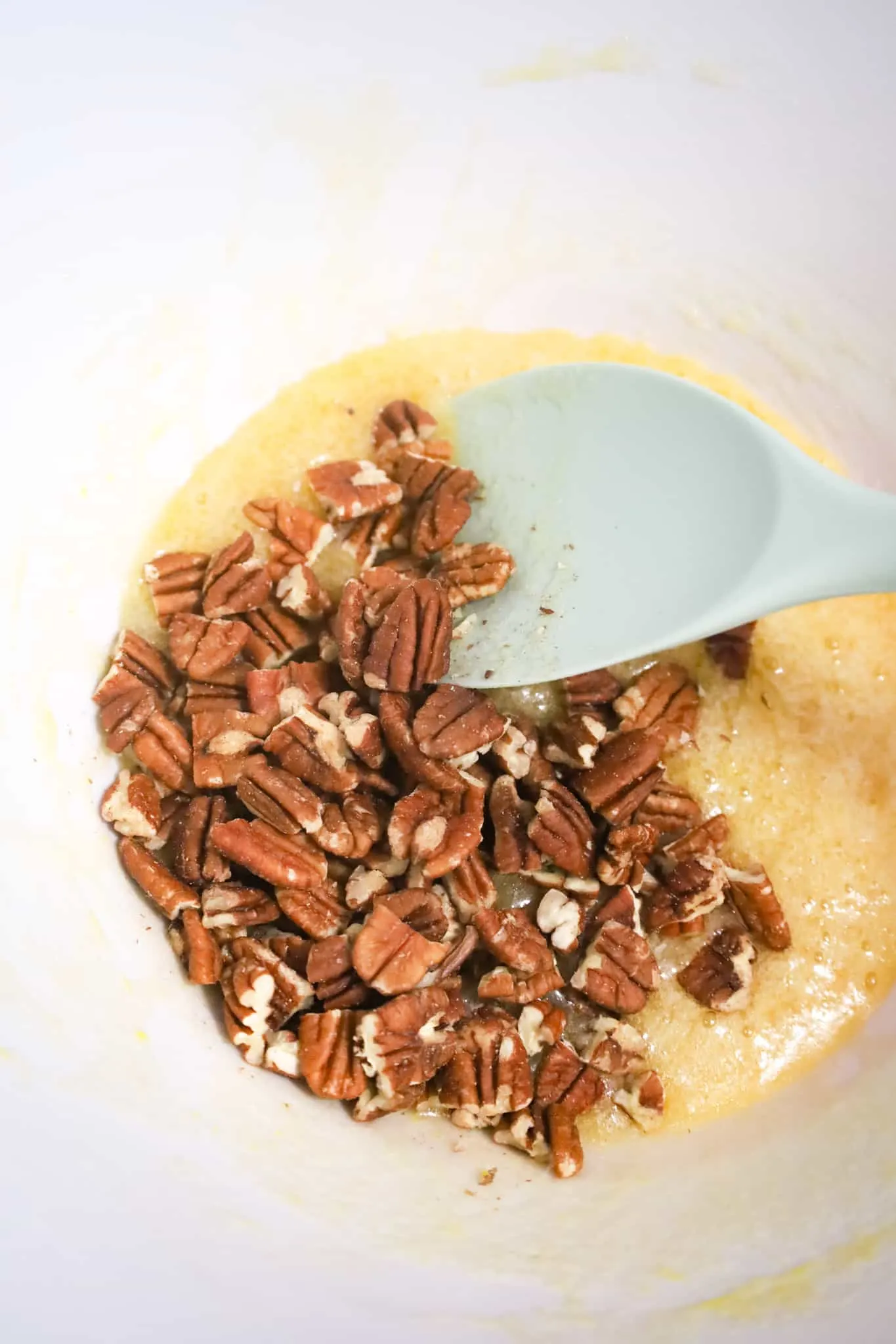 chopped pecans on top of corn syrup, butter and sugar mixture in a mixing bowl