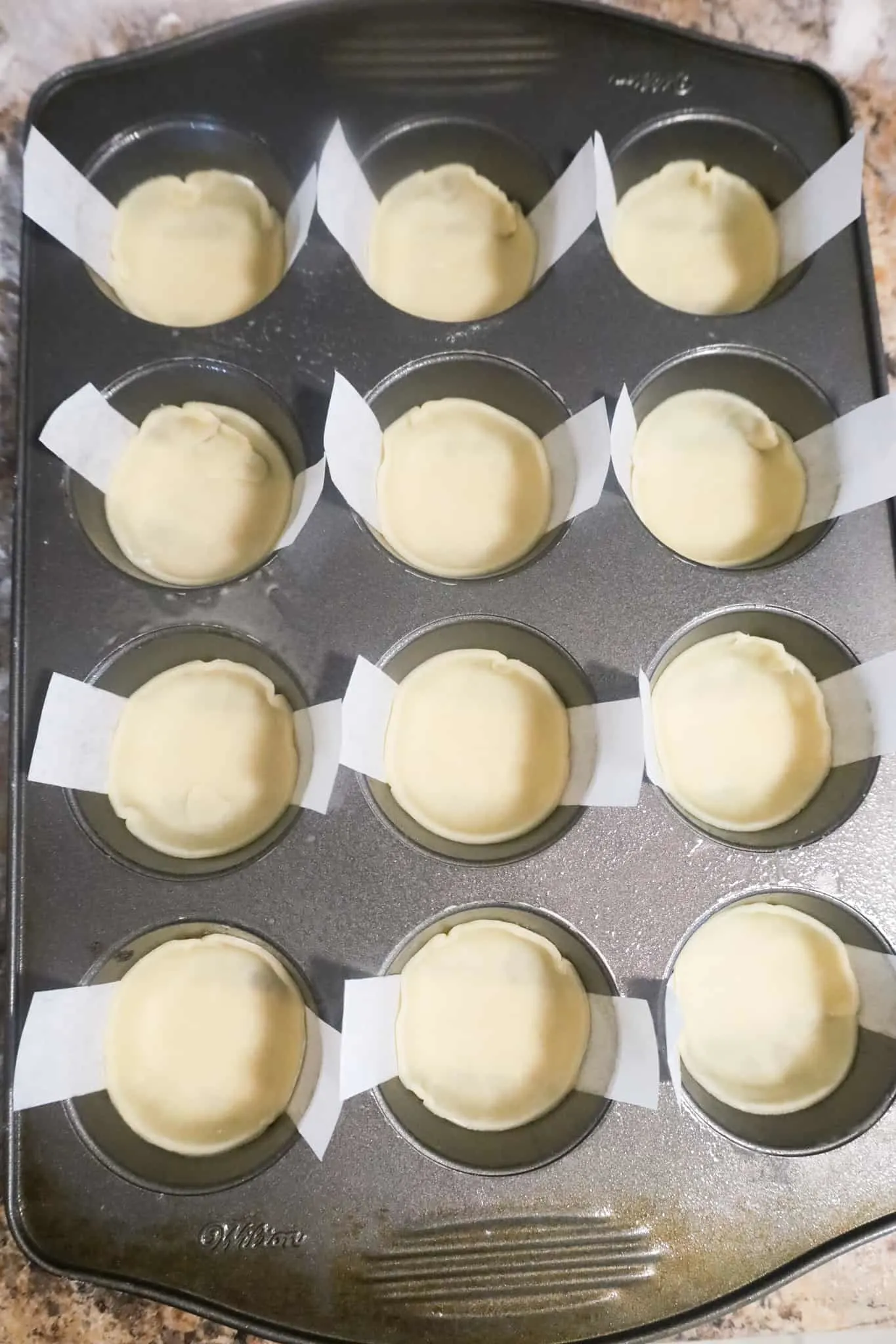 pastry in muffin tins with parchment paper strips