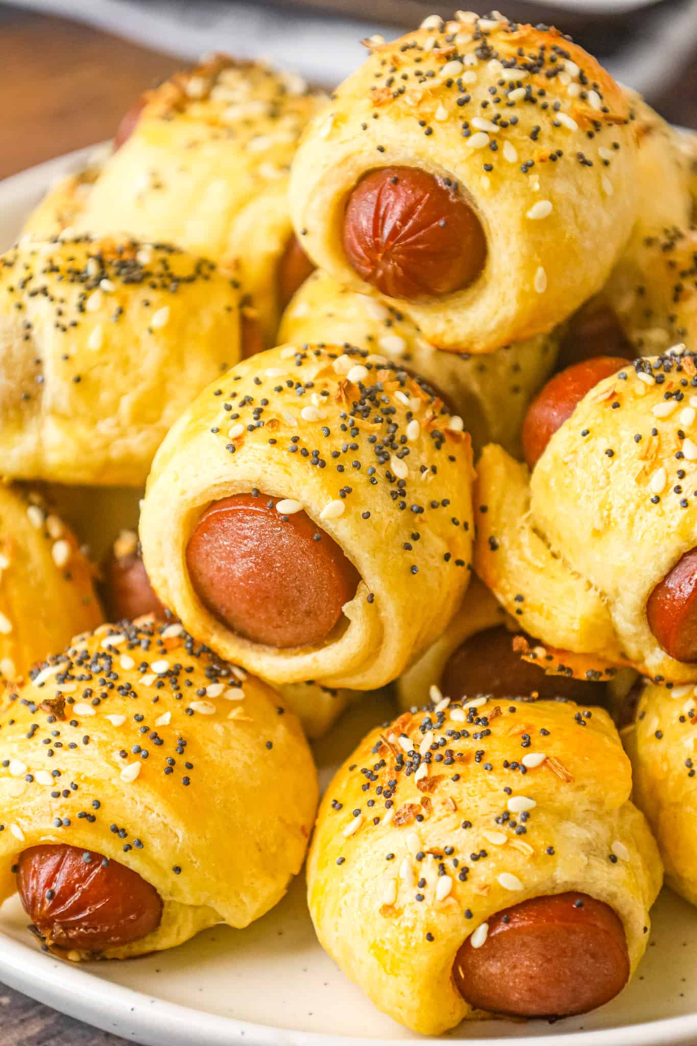 Pigs in a Blanket are a delicious bite sized party food or kid friendly dinner recipe using wieners and Pillsbury crescent roll dough topped with poppy seeds, sesame seeds and dehydrated minced onions.