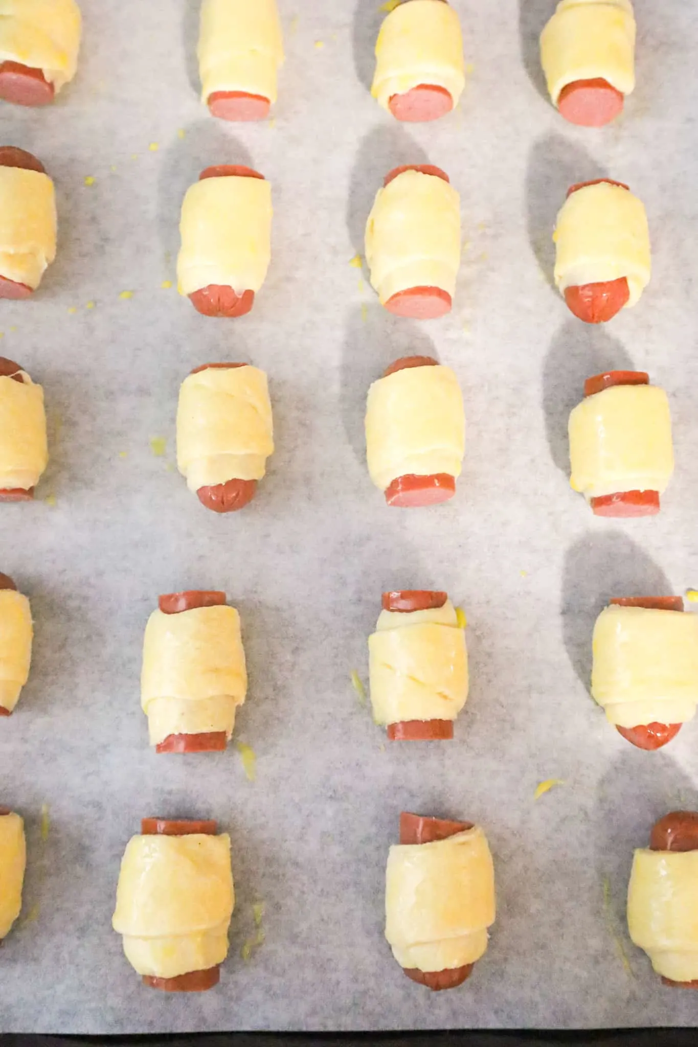 hot dog pieces wrapped in crescent dough and brushed with egg wash