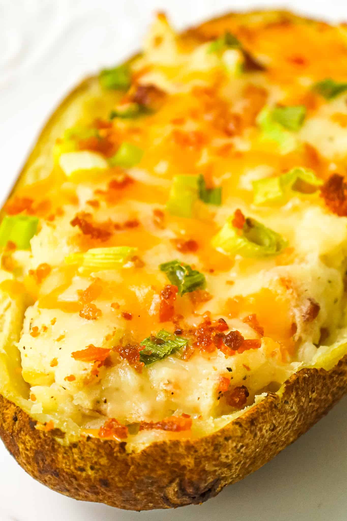Twice Baked Potatoes are a delicious side dish recipe of potato skins filled with mashed potatoes loaded with cheese, crumbled bacon, sour cream and green onions.