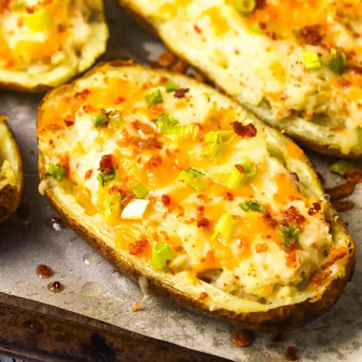 Twice Baked Potatoes are a delicious side dish recipe of potato skins filled with mashed potatoes loaded with cheese, crumbled bacon, sour cream and green onions.