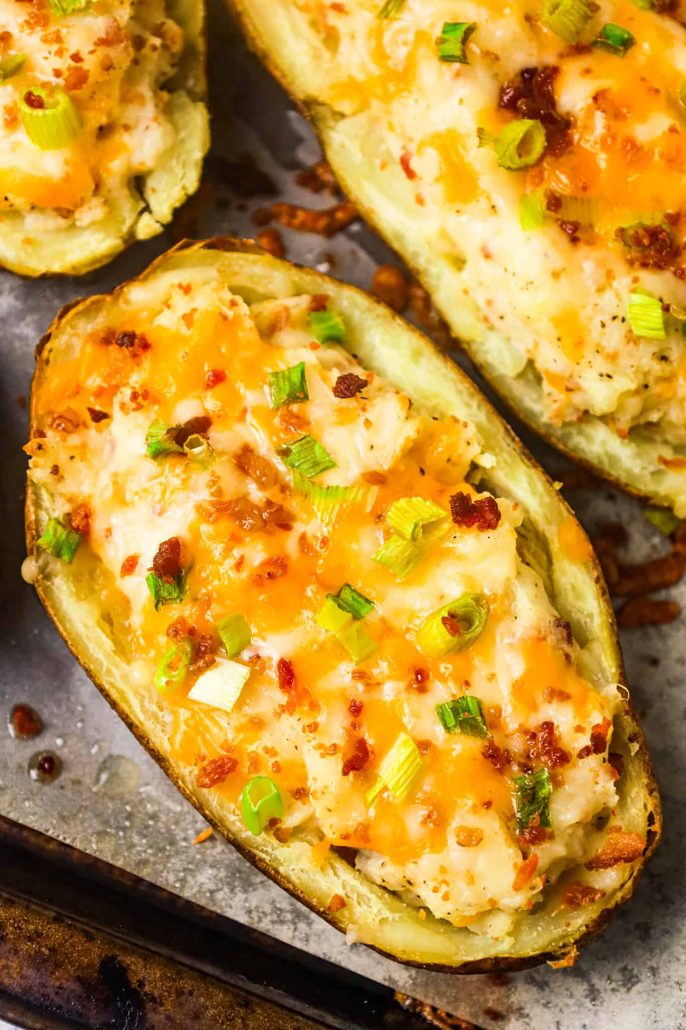 Twice Baked Potatoes are a delicious side dish recipe of potato skins filled with mashed potatoes loaded with cheese, crumbled bacon, sour cream and green onions.