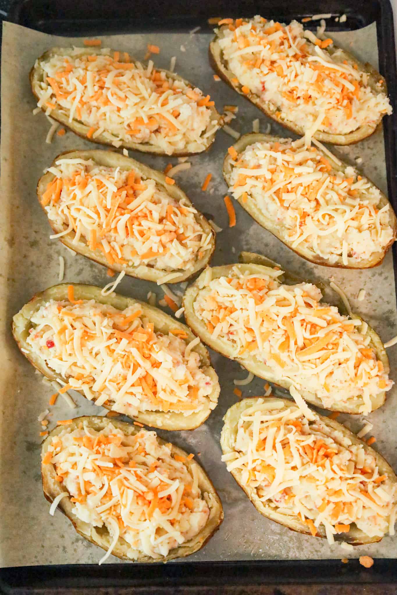 shredded cheese on top of mashed potato in potato skins