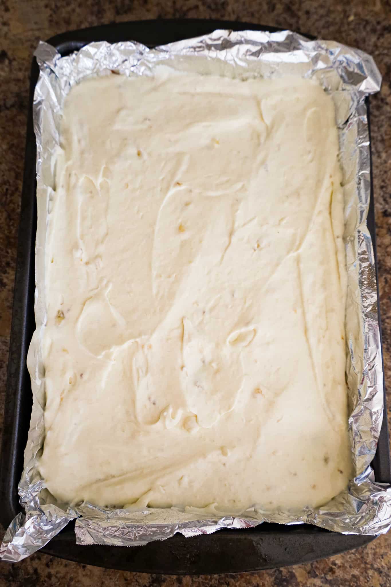 banana pudding mixture spread on top of brownies in a baking pan
