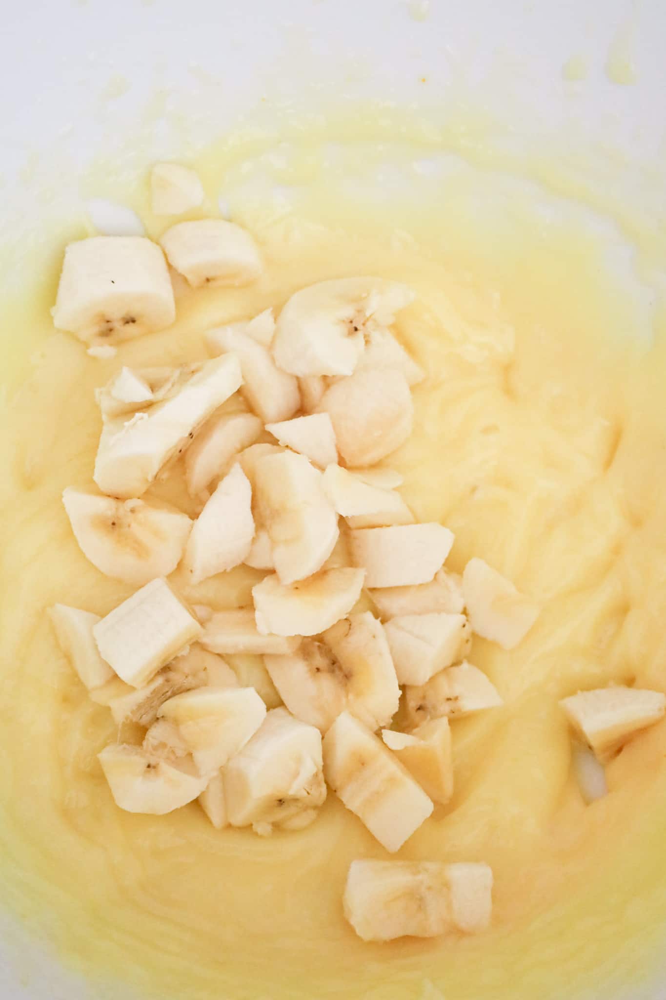 chopped banana on top of vanilla pudding mixture in a mixing bowl