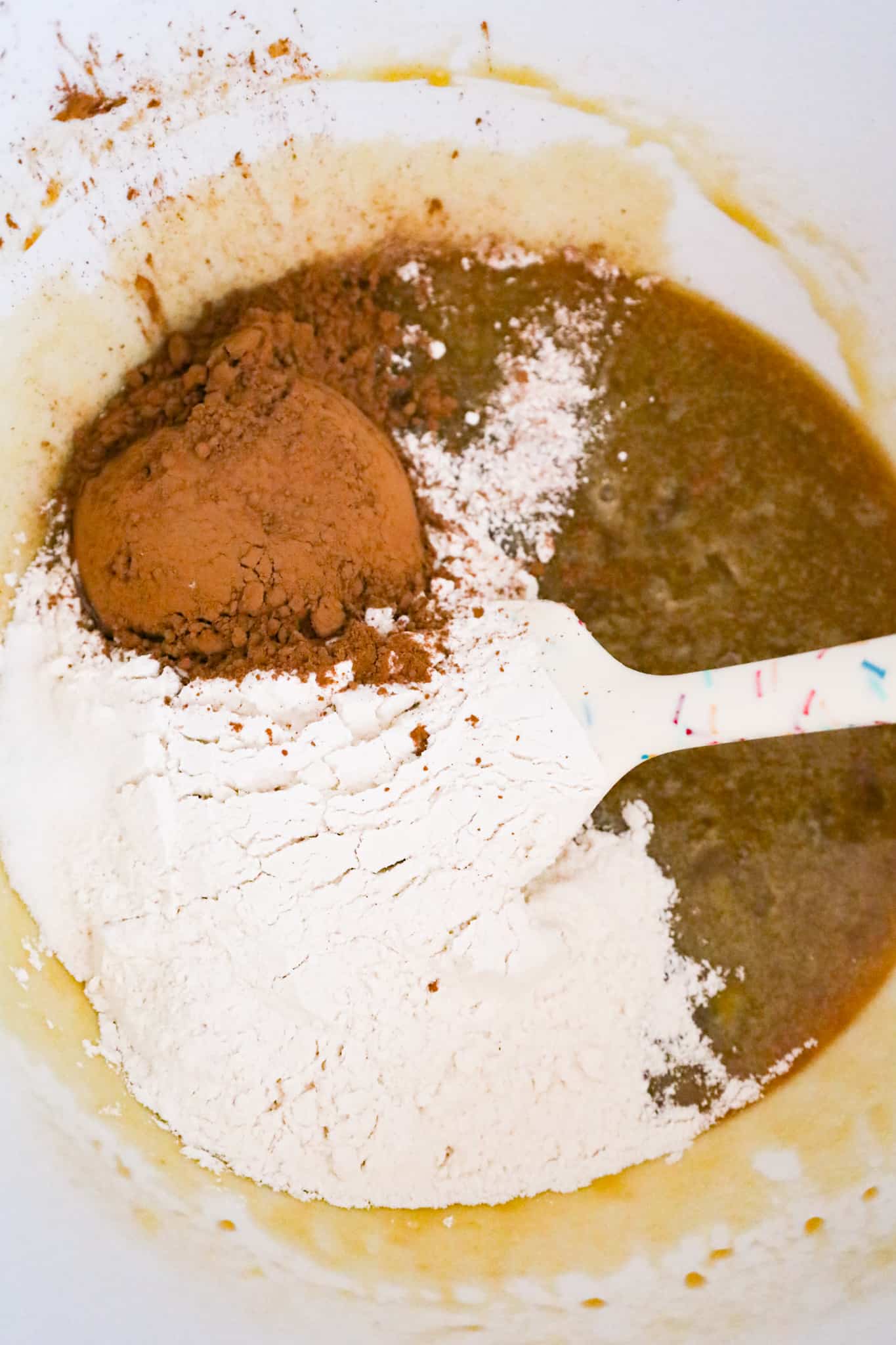 all purpose flour and cocoa powder on top of sugar and butter mixture in a mixing bowl