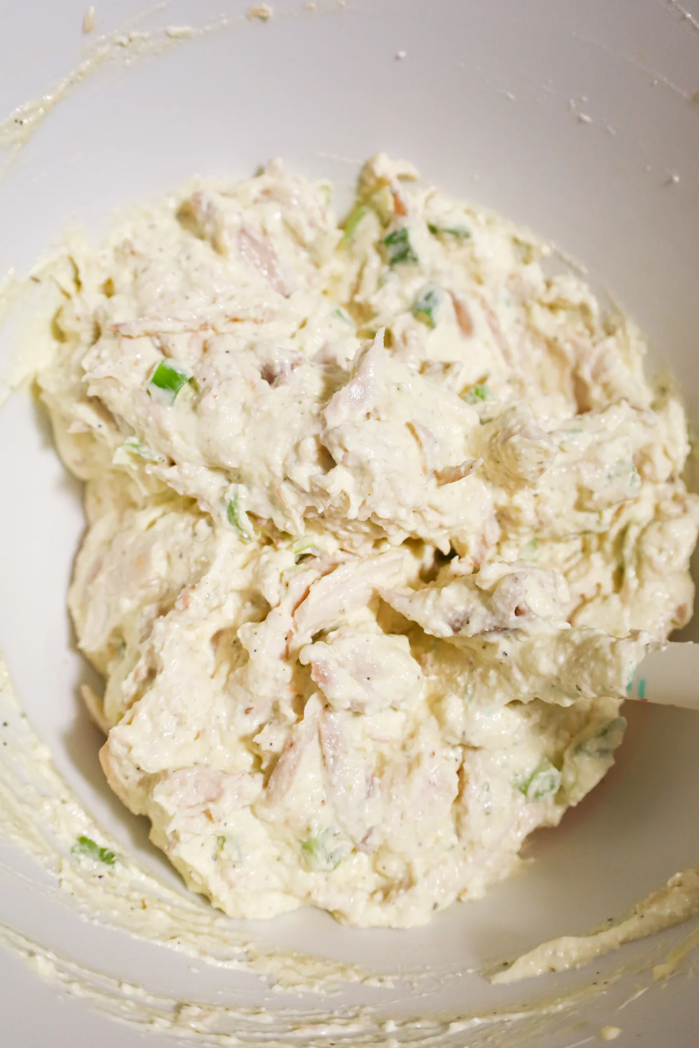 creamy chicken mixture with green onions in a mixing bowl