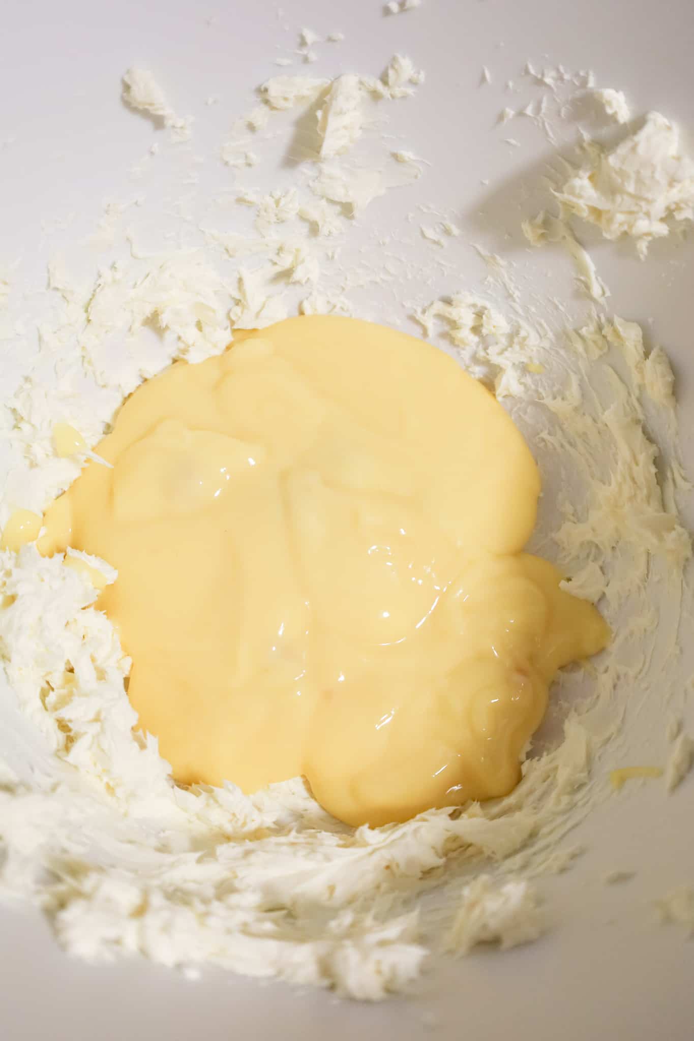 cream of chicken soup on top of whipped cream cheese in a mixing bowl