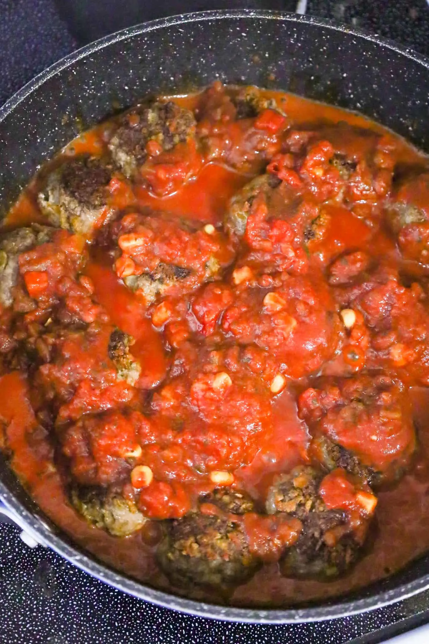 salsa and tomato sauce on top of meatballs cooking in a skillet