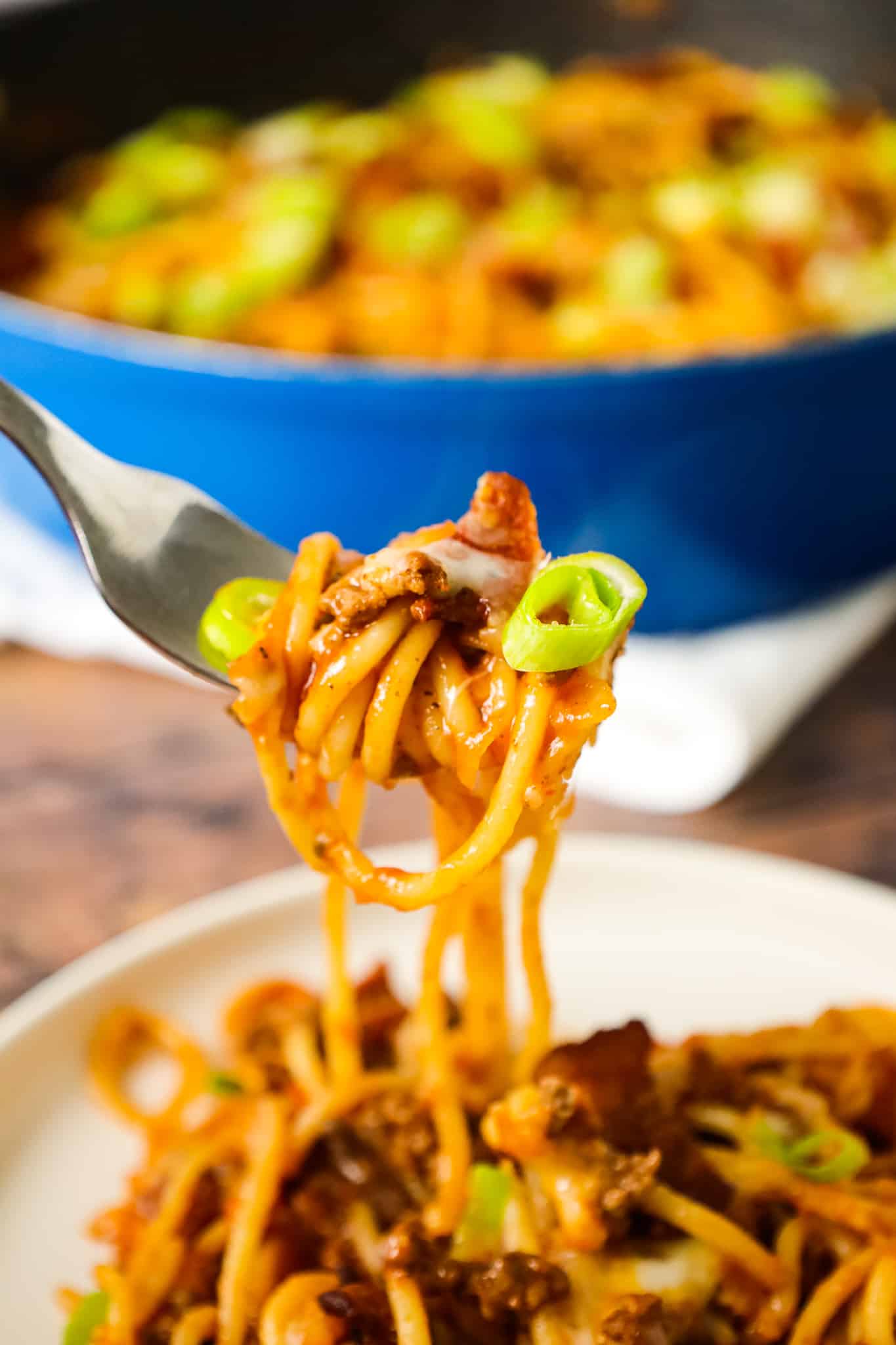 Cowboy Spaghetti is a hearty pasta recipe loaded with bacon, ground beef, Rotel diced tomatoes and green chilies, tomato sauce, bbq sauce, shredded cheese and chopped green onions.
