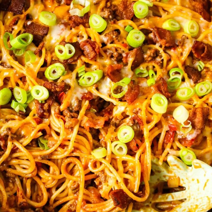 Cowboy Spaghetti is a hearty pasta recipe loaded with bacon, ground beef, Rotel diced tomatoes and green chilies, tomato sauce, bbq sauce, shredded cheese and chopped green onions.