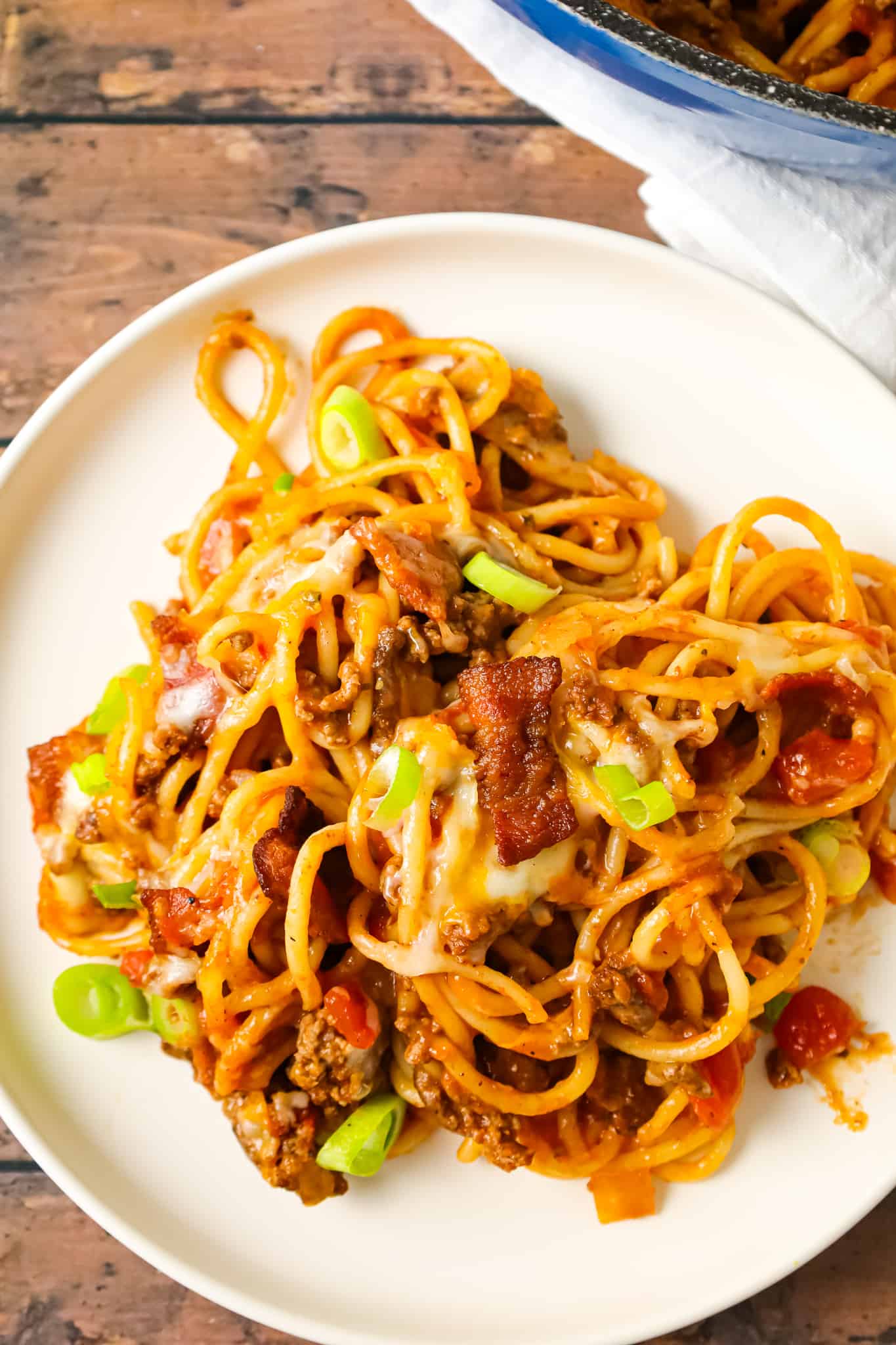 Cowboy Spaghetti is a hearty pasta recipe loaded with bacon, ground beef, Rotel diced tomatoes and green chilies, tomato sauce, bbq sauce, shredded cheese and chopped green onions.