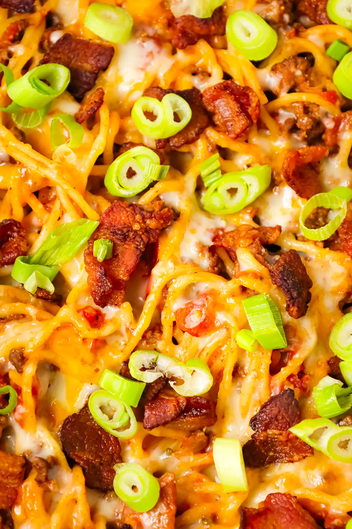 Cowboy Spaghetti is a hearty pasta recipe loaded with bacon, ground beef, Rotel diced tomatoes and green chilies, tomato sauce, bbq sauce, shredded cheese and chopped green onions.