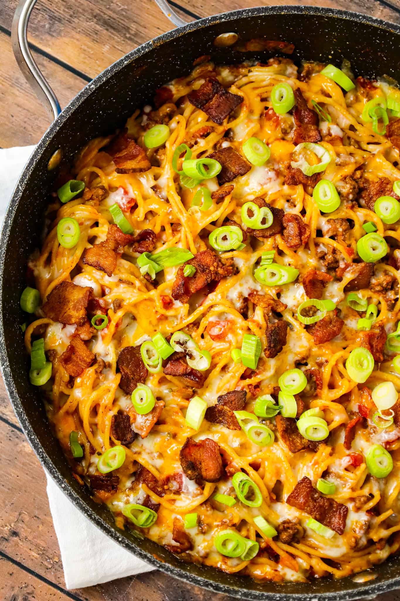 Cowboy Spaghetti is a hearty pasta recipe loaded with bacon, ground beef, Rotel diced tomatoes and green chilies, tomato sauce, bbq sauce, shredded cheese and chopped green onions.