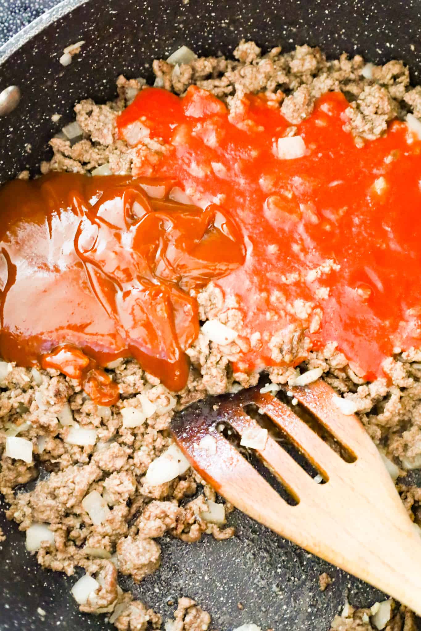 tomato sauce and bbq sauce on top of cooked ground beef in a skillet