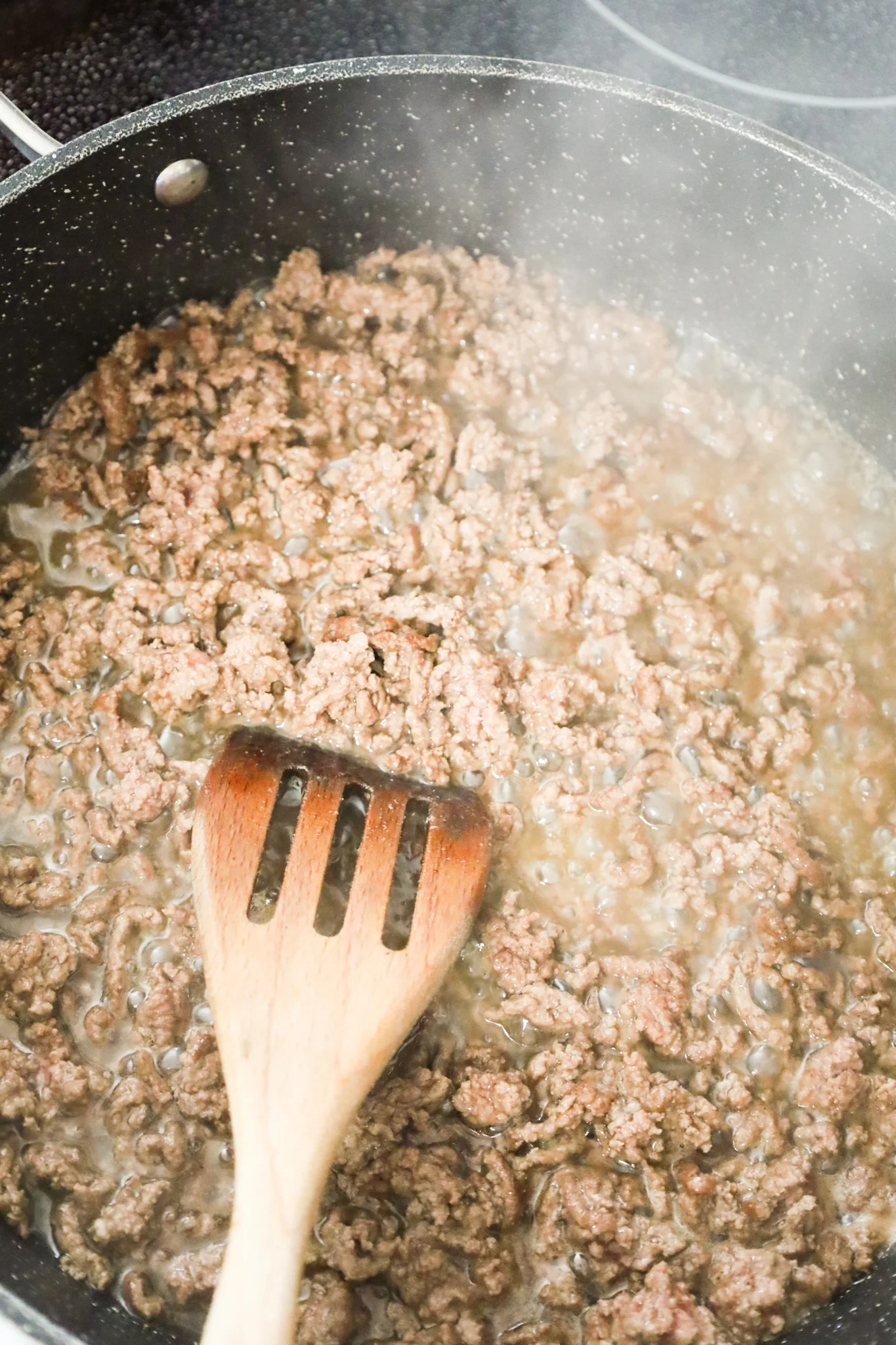 ground beef cooking in bacon grease in a skillet