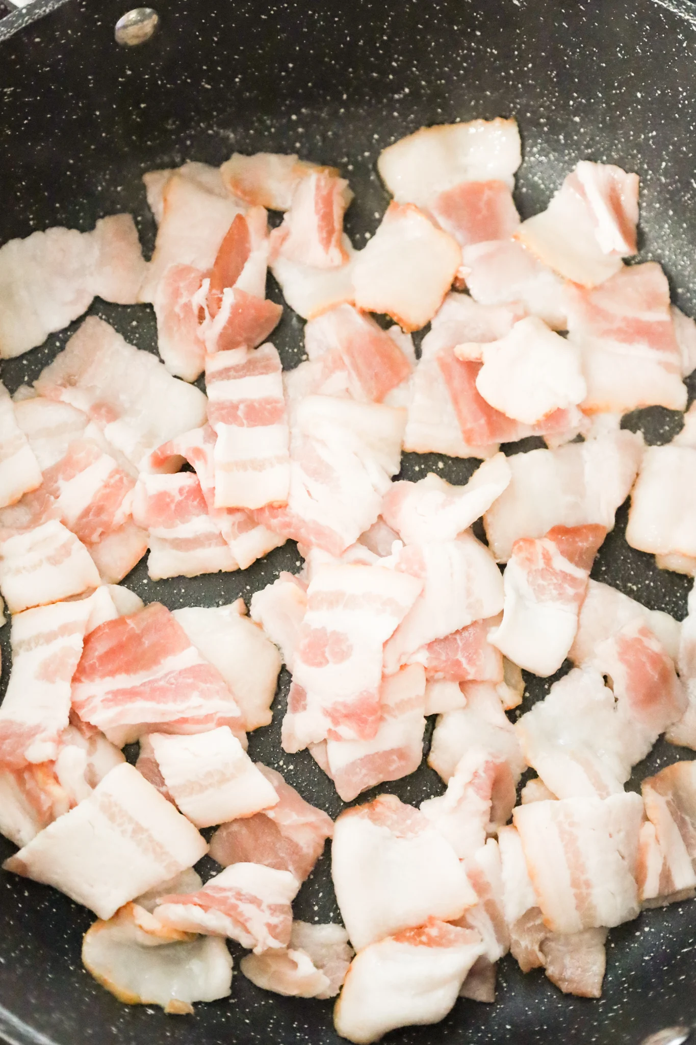 raw bacon pieces in a skillet