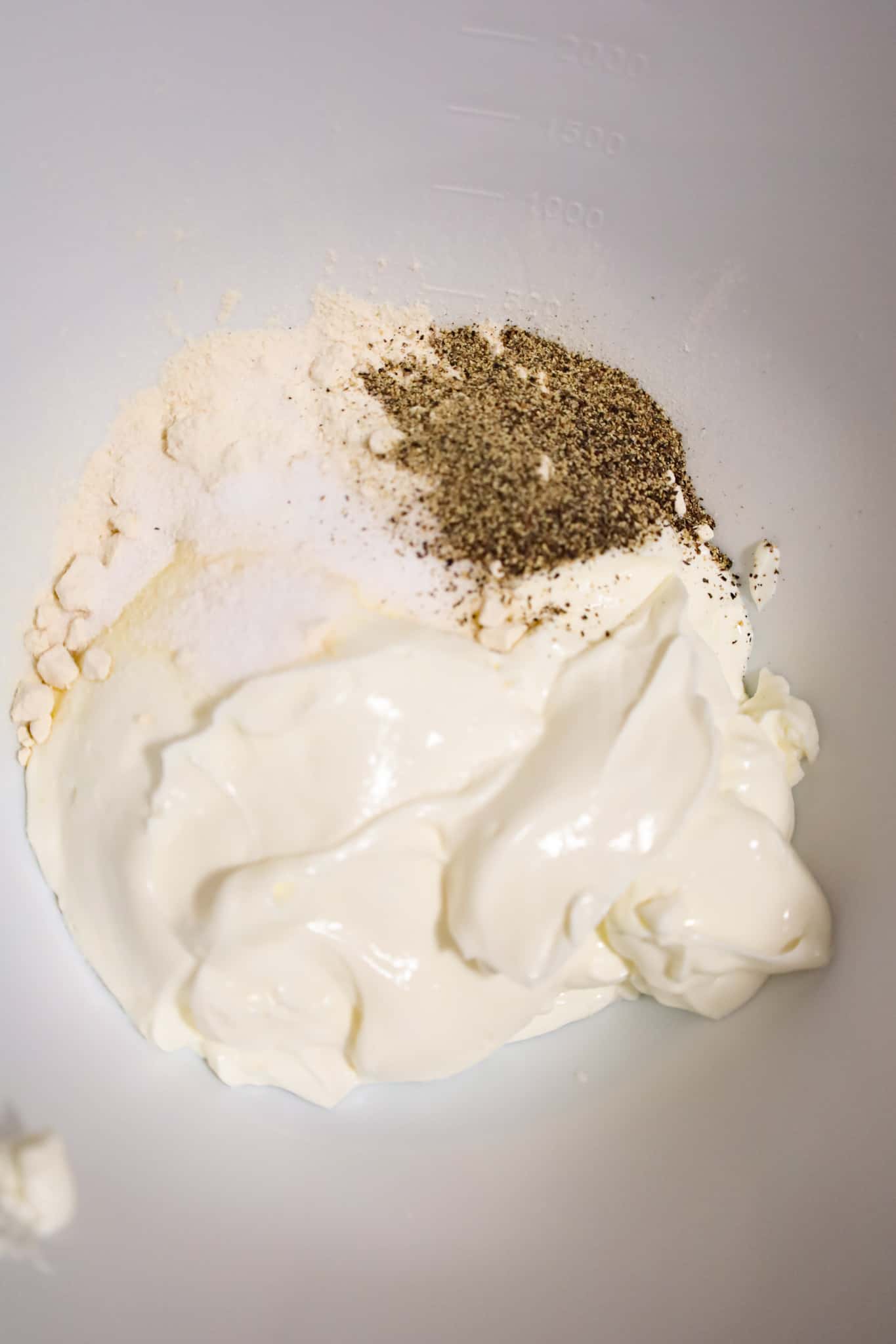 spices on top of sour cream in a mixing bowl