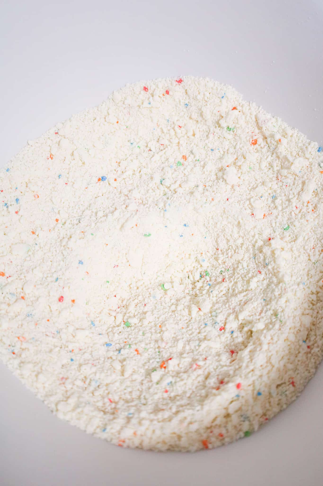 frosting and funfetti cake mix combined in a mixing bowl