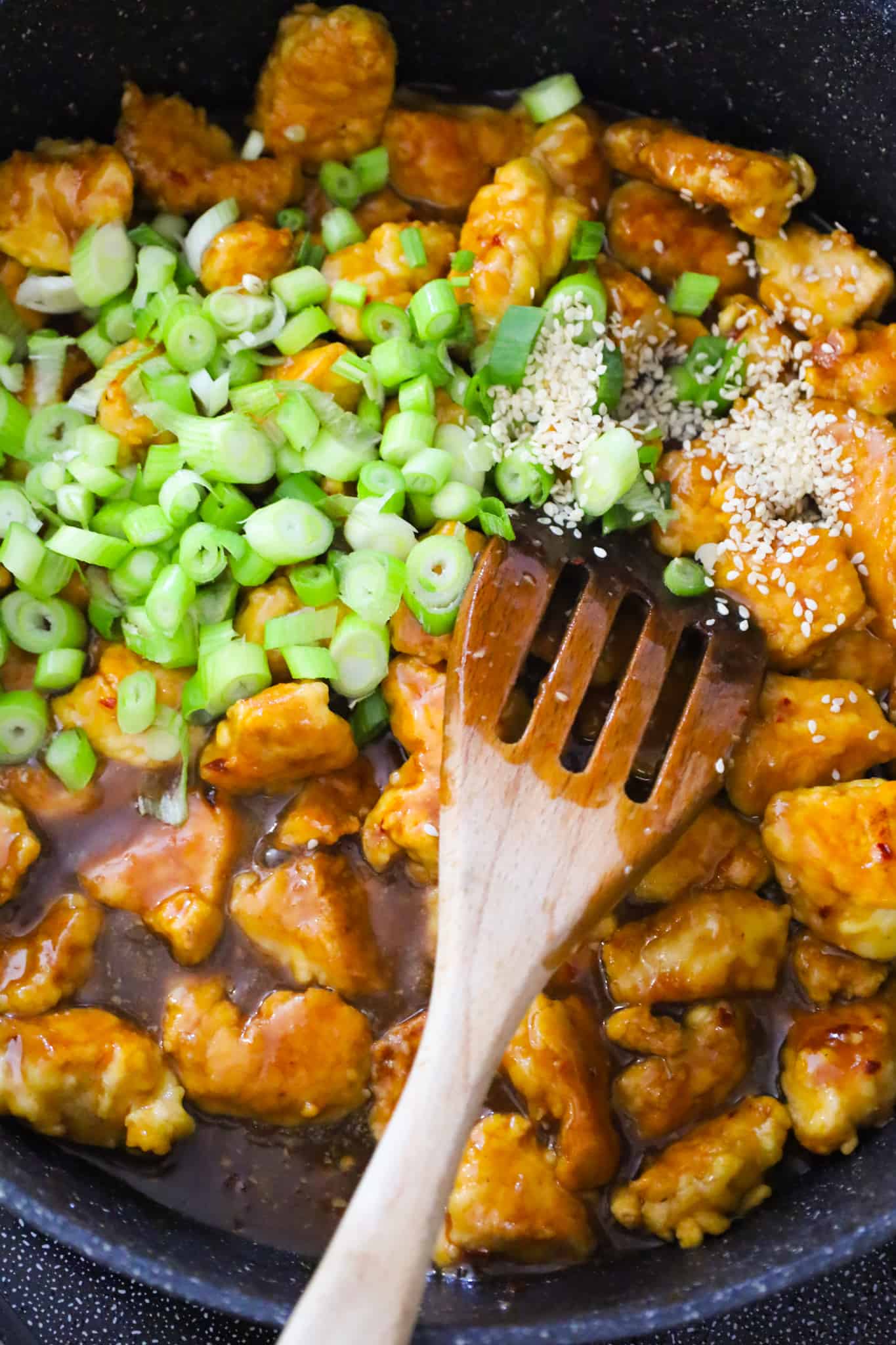 sesame seeds and chopped green onions on top of Empress chicken in a skillet