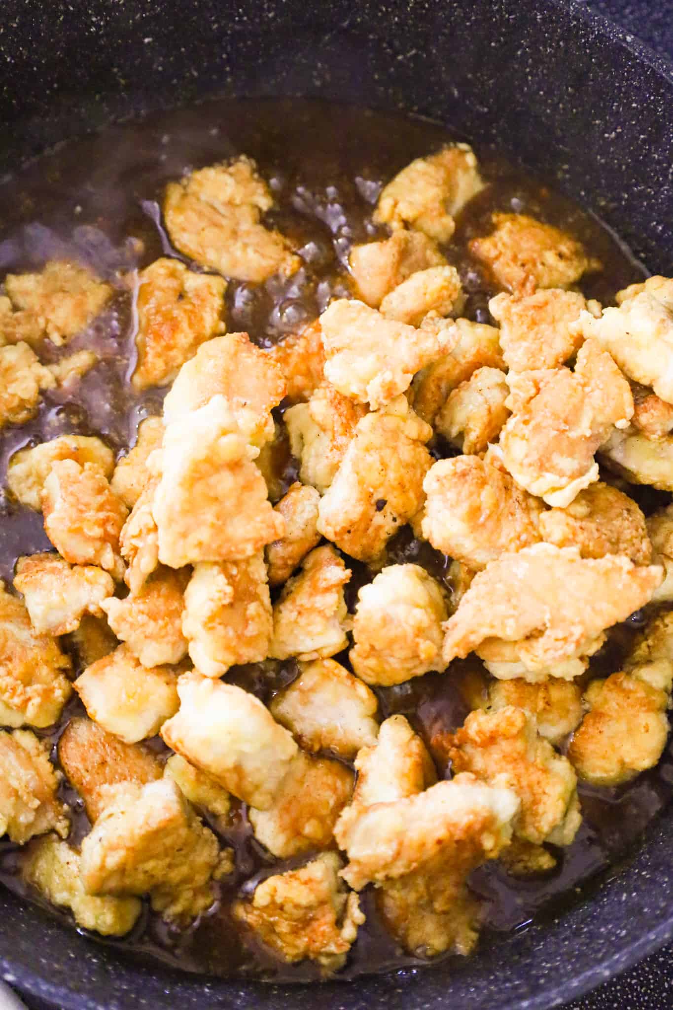cooked chicken breast chunks added to skillet with spicy sweet and sour sauce