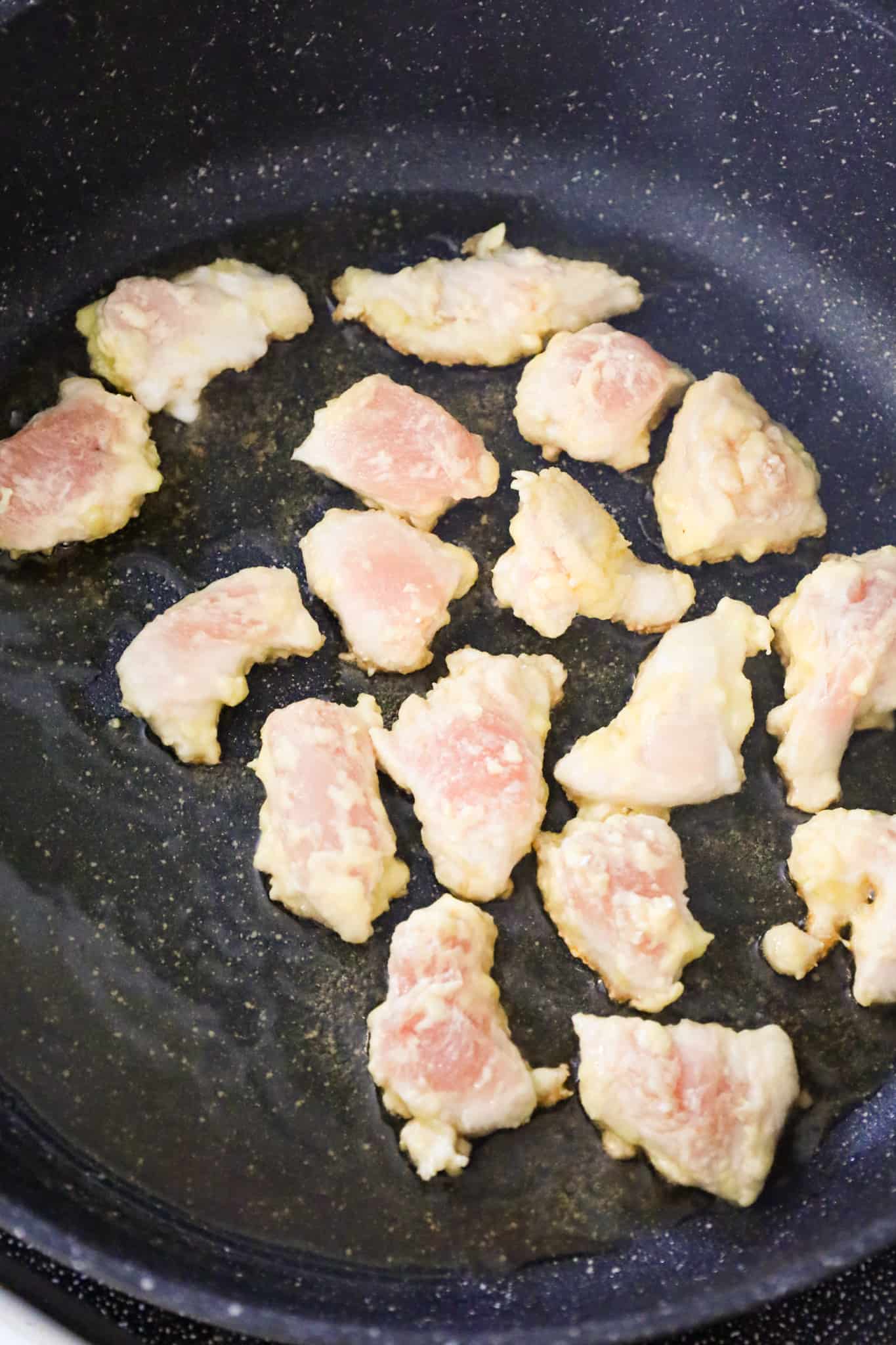 chicken breast chunks cooking in a skillet