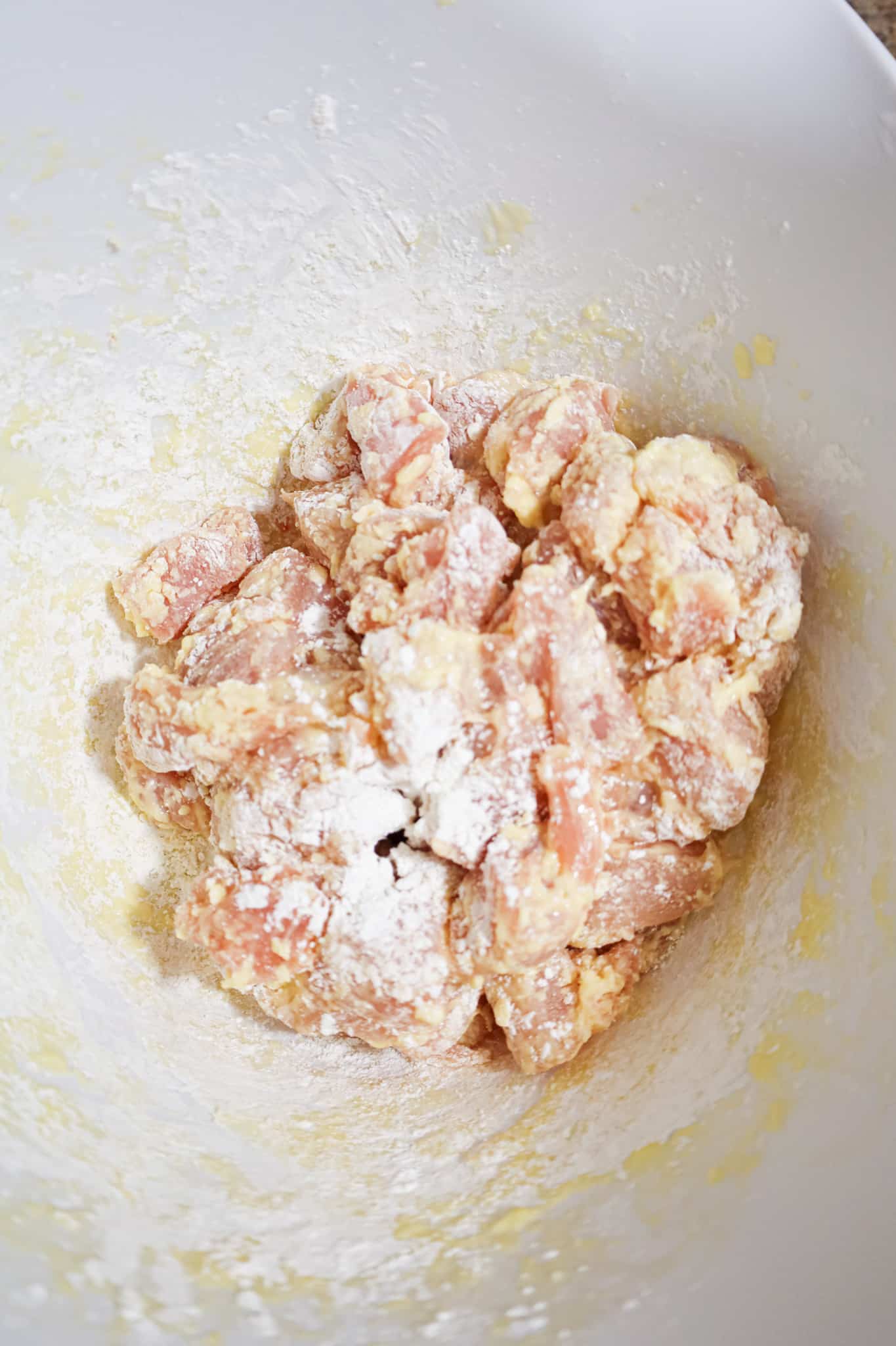 egg and corn starch coated chicken chunks in a mixing bfowl