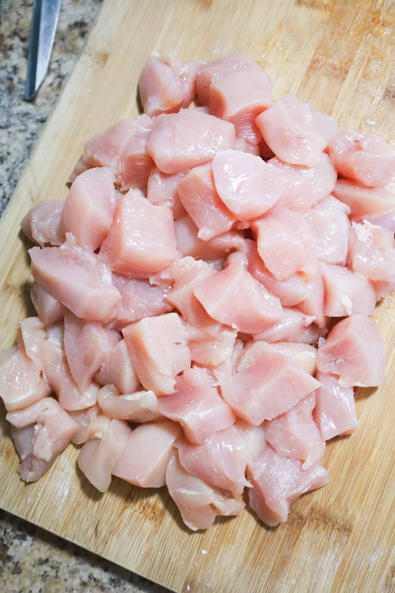 raw chicken breast chunks on a cutting board