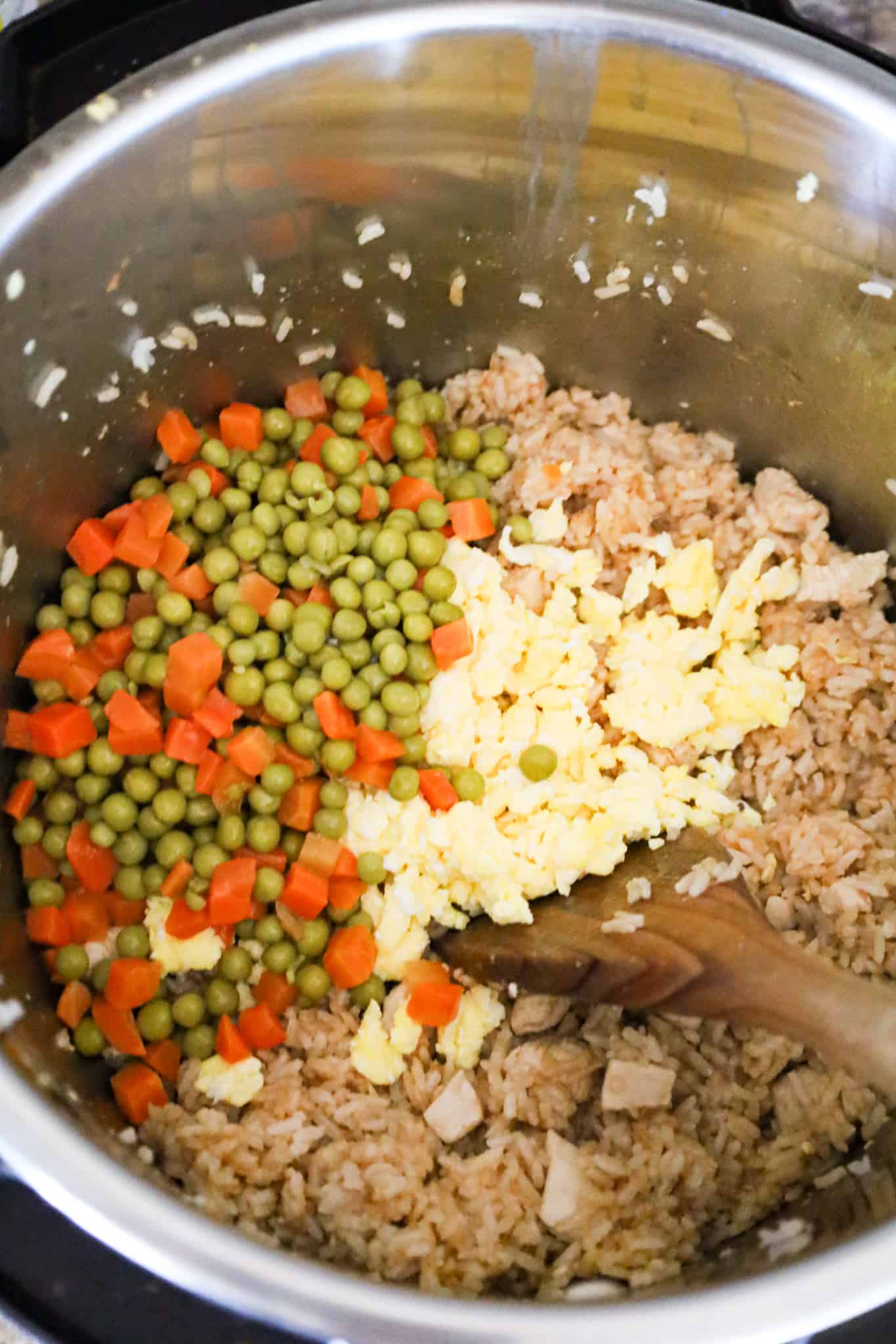 canned peas and carrots and cooked egg on top of chicken and rice in an Instant Pot