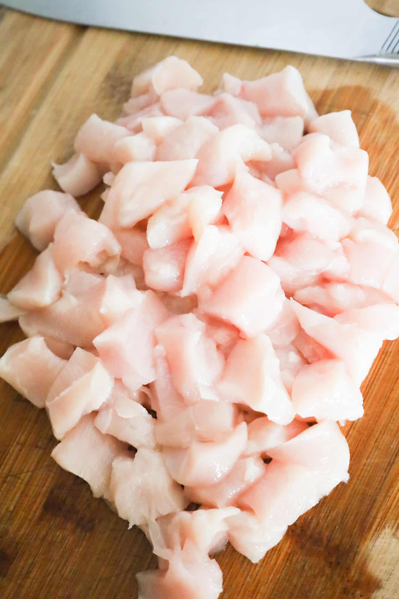 raw diced chicken breast on a cutting board