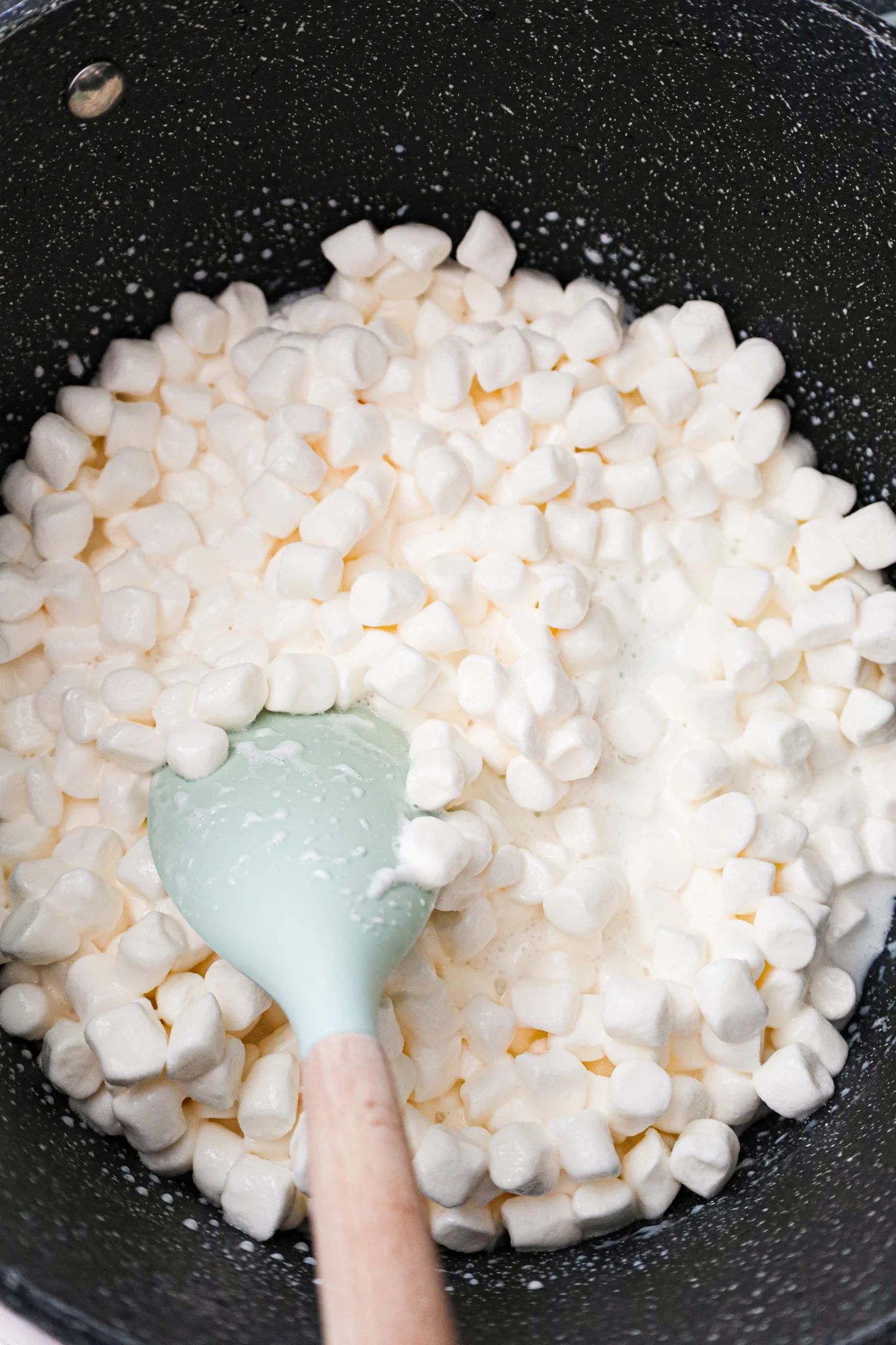 milk and mini marshmallows being stirred in a large sauce pot