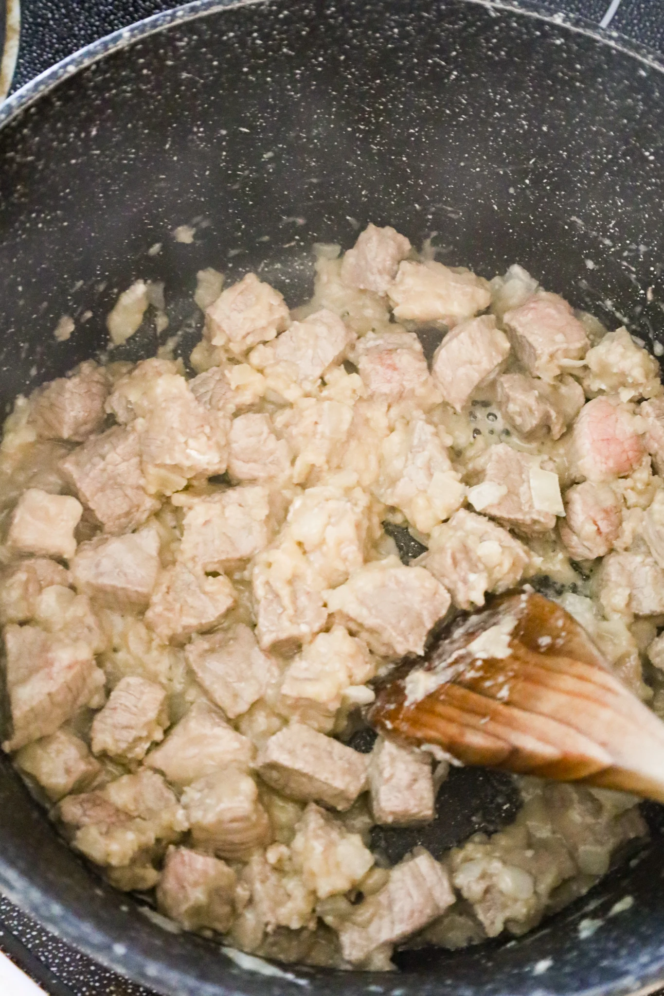 steak chunks coated in flour mixture cooking in a pot