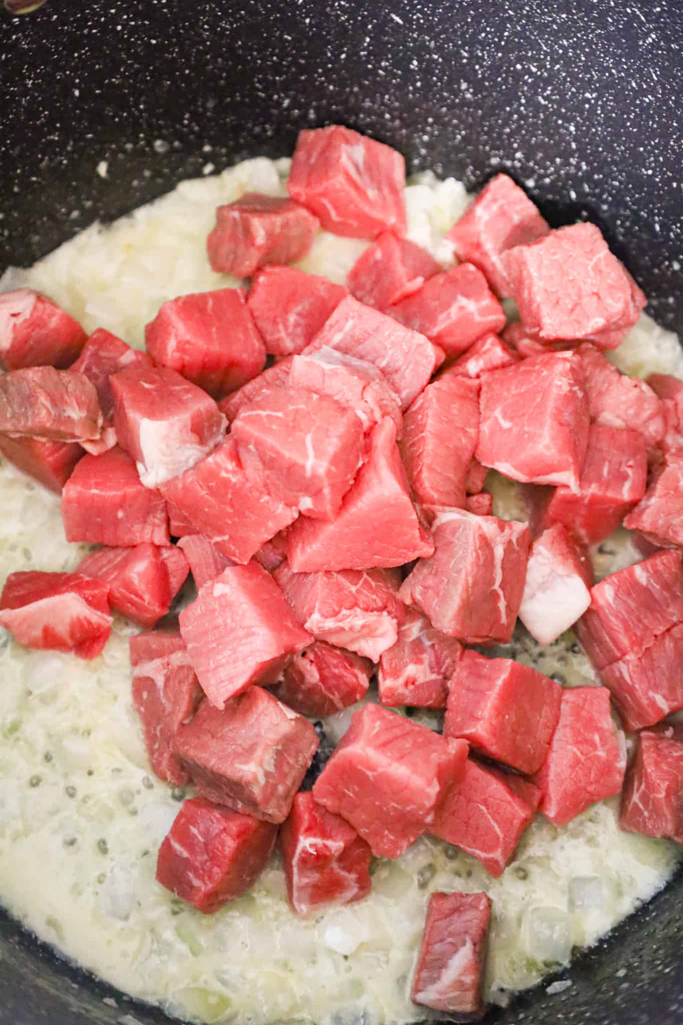 raw steak chunks added to pot with melted butter