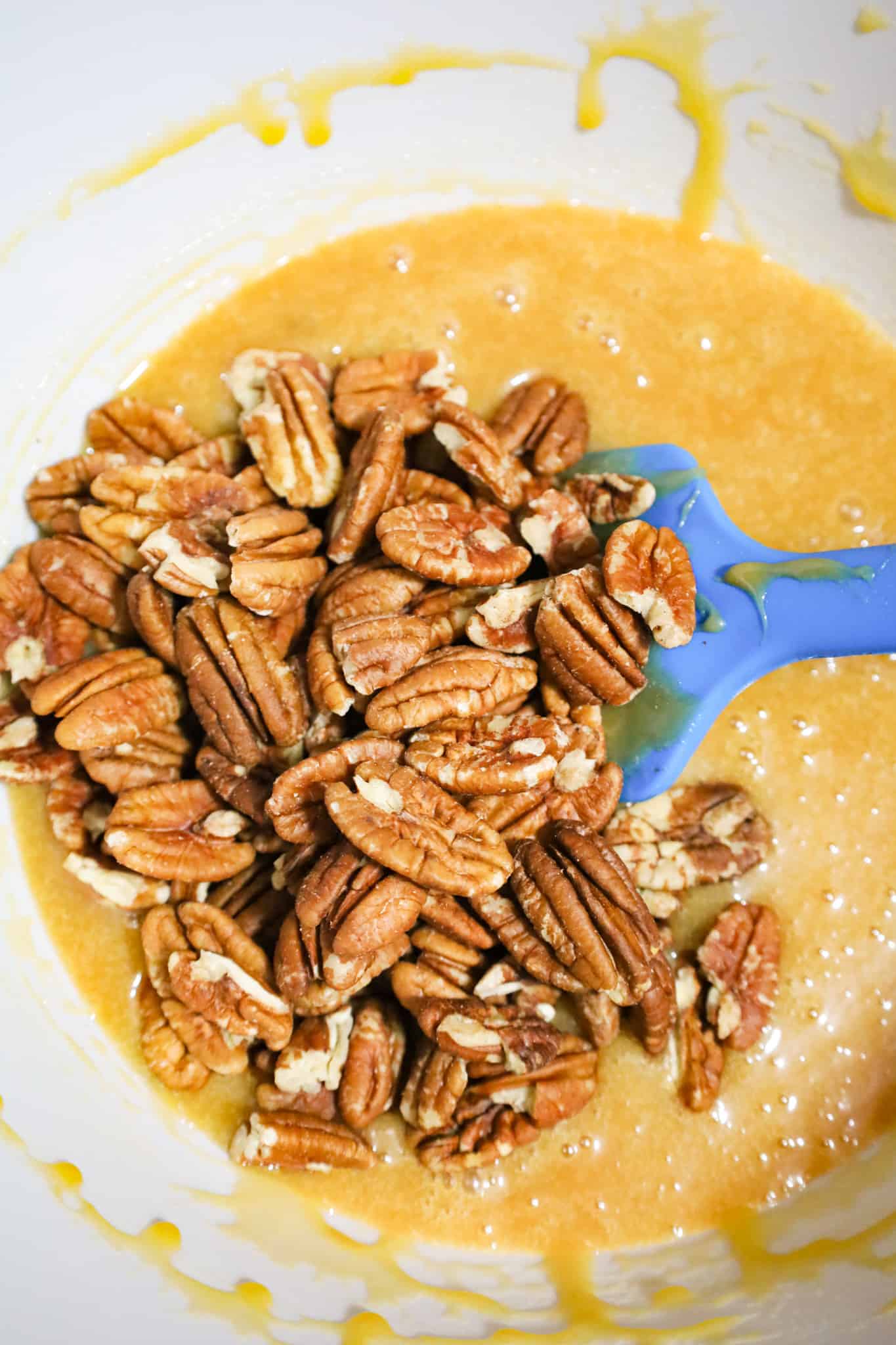 pecan halves on top of caramel pie filling mixture in a mixing bowl