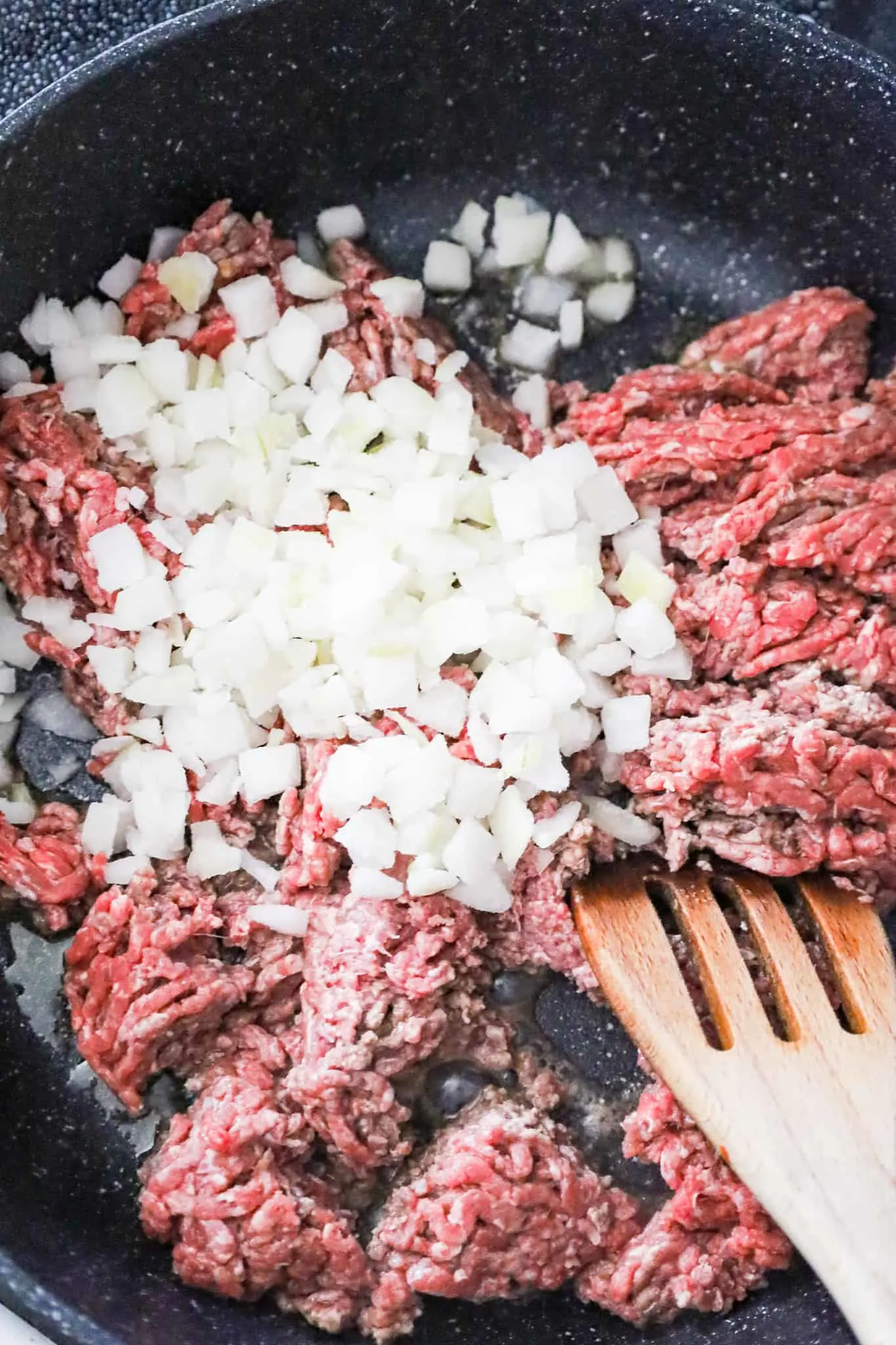 diced onions and raw ground beef in a skillet