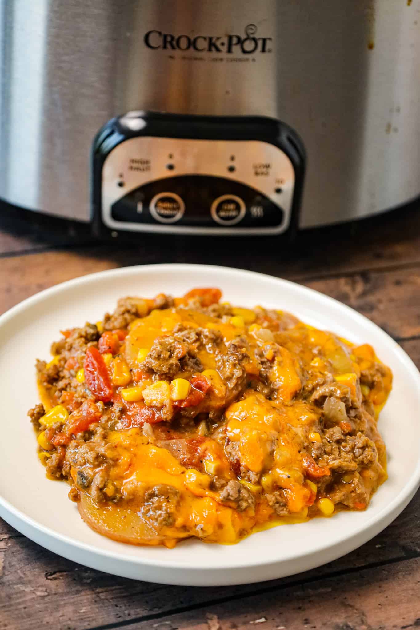 Crock Pot Cowboy Casserole is a hearty slow cooker dinner recipe loaded with ground beef, diced tomatoes, potatoes, corn and cheese.