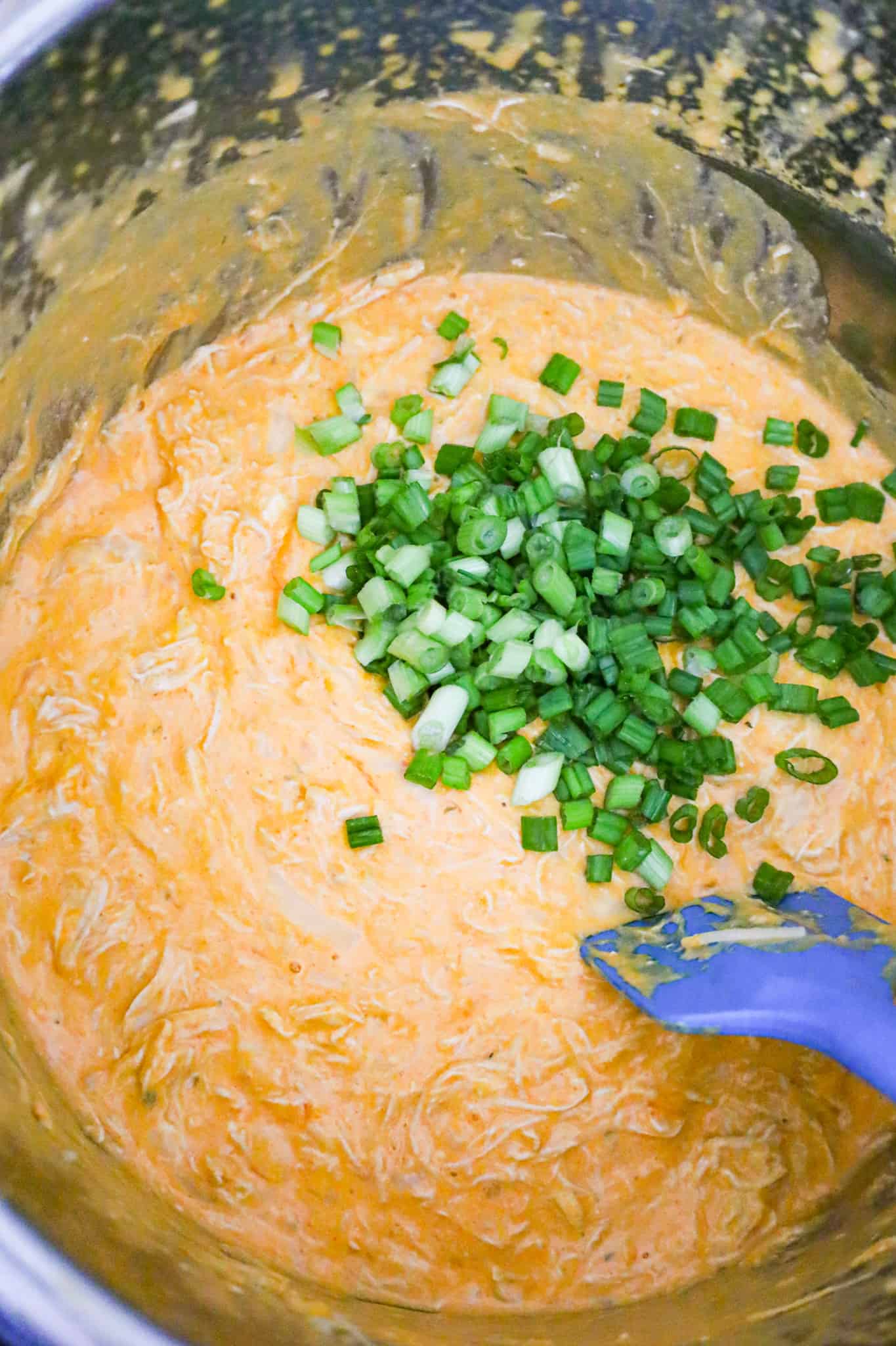 chopped green onions on top of Buffalo chicken dip in an Instant Pot