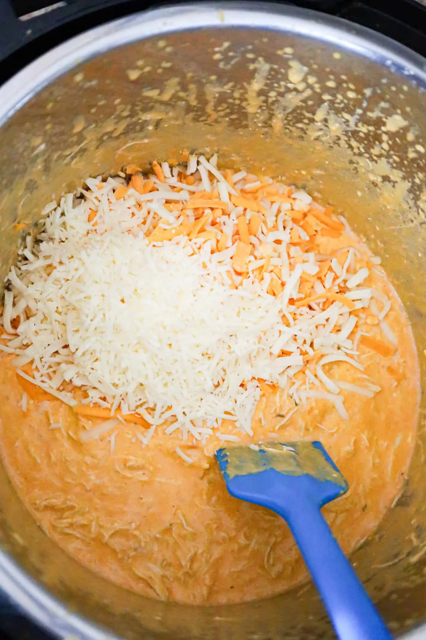 shredded cheese on top of Buffalo chicken dip in an Instant Pot