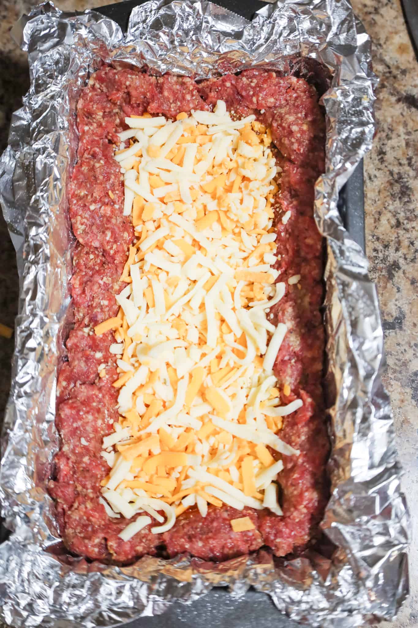 shredded cheese in the center of meatloaf mixture in a loaf pan