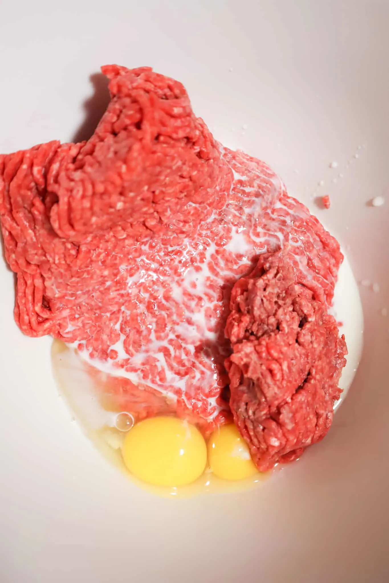 milk, eggs and lean ground beef in a mixing bowl