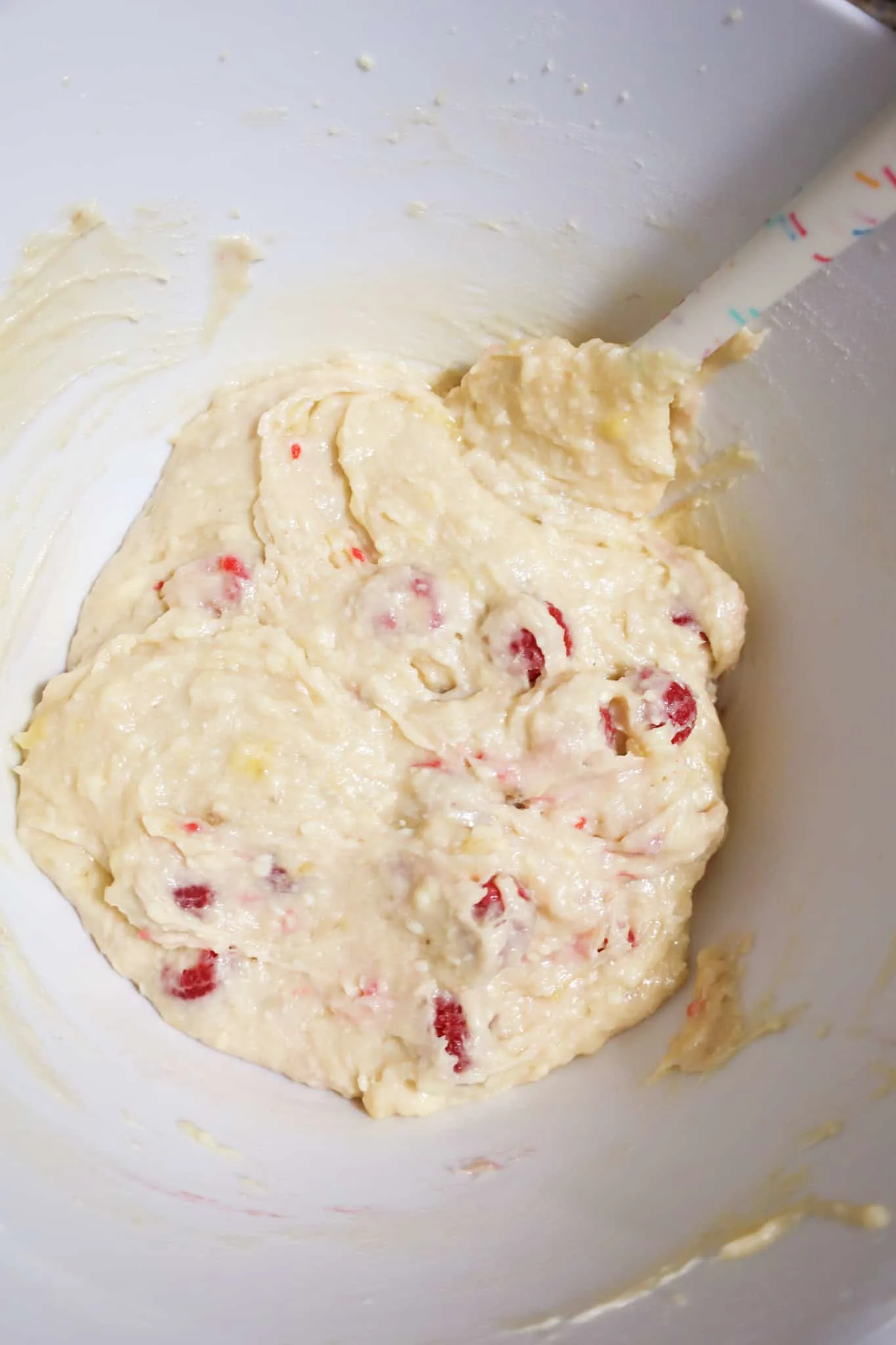 raspberries stirred into banana bread batter in a mixing bowl