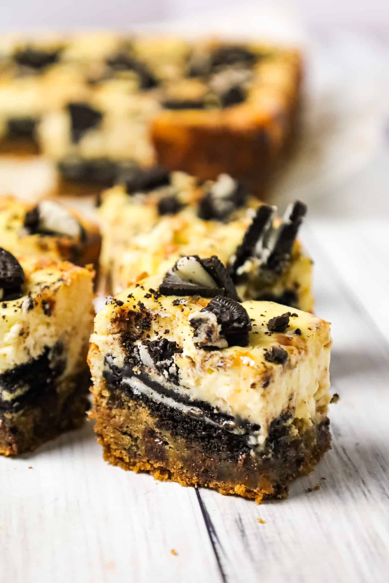 Slutty Cheesecake Bars are a decadent dessert recipe with a base of chocolate chip cookie dough topped with Oreo cookies, cheesecake and Skor toffee bits.